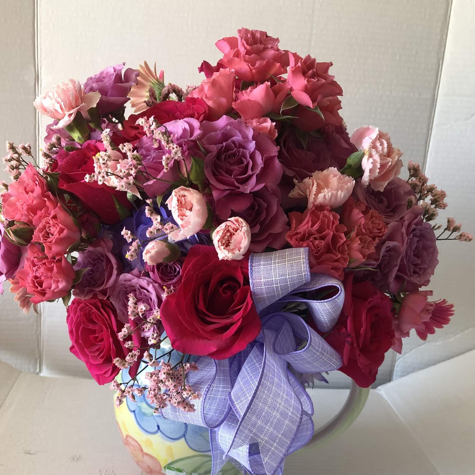 A lovely pitcher filled with hot pink, pink, and lavender blooms.