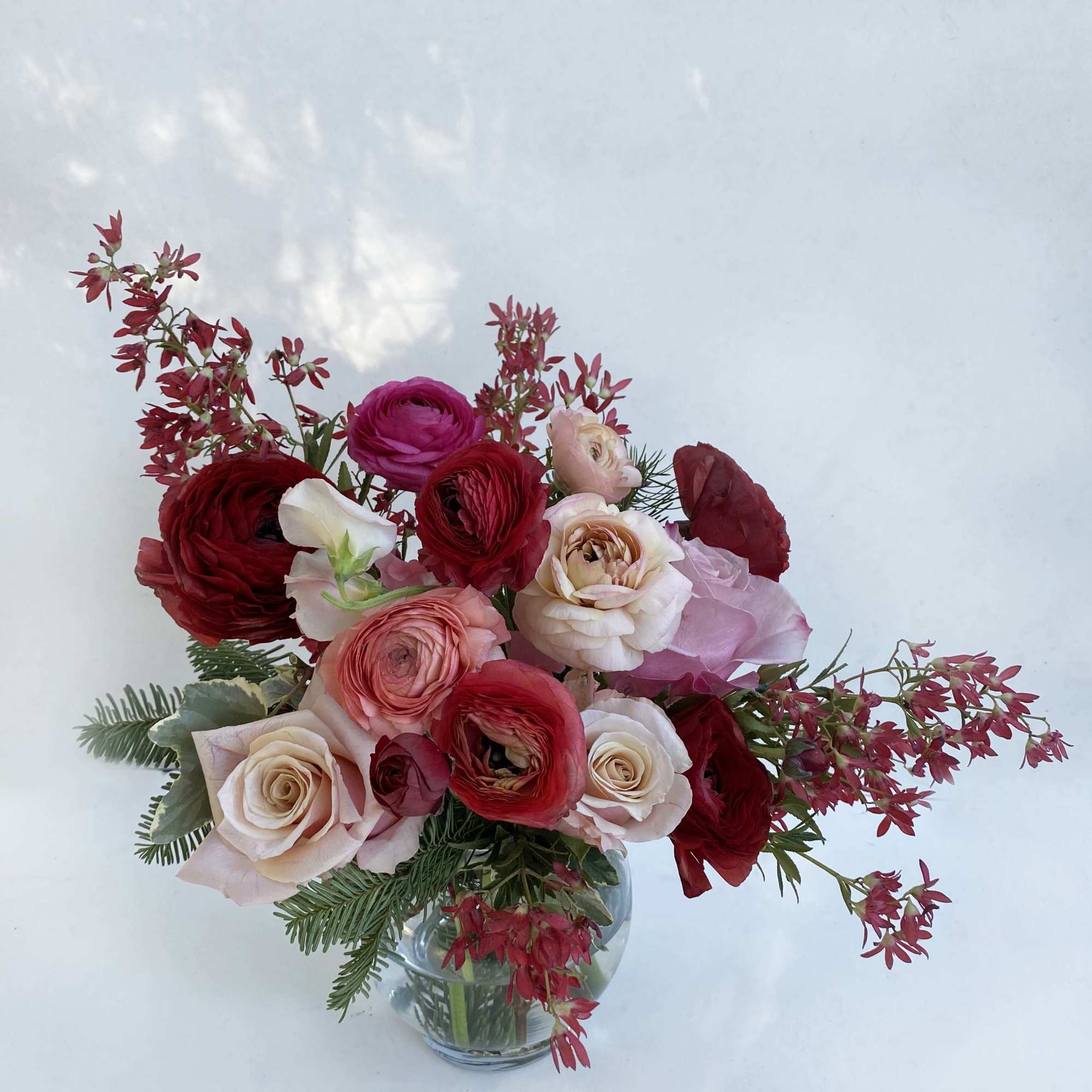 Beautiful warm blushing colors adorn this arrangement of ranunuclus, roses, and seasonal