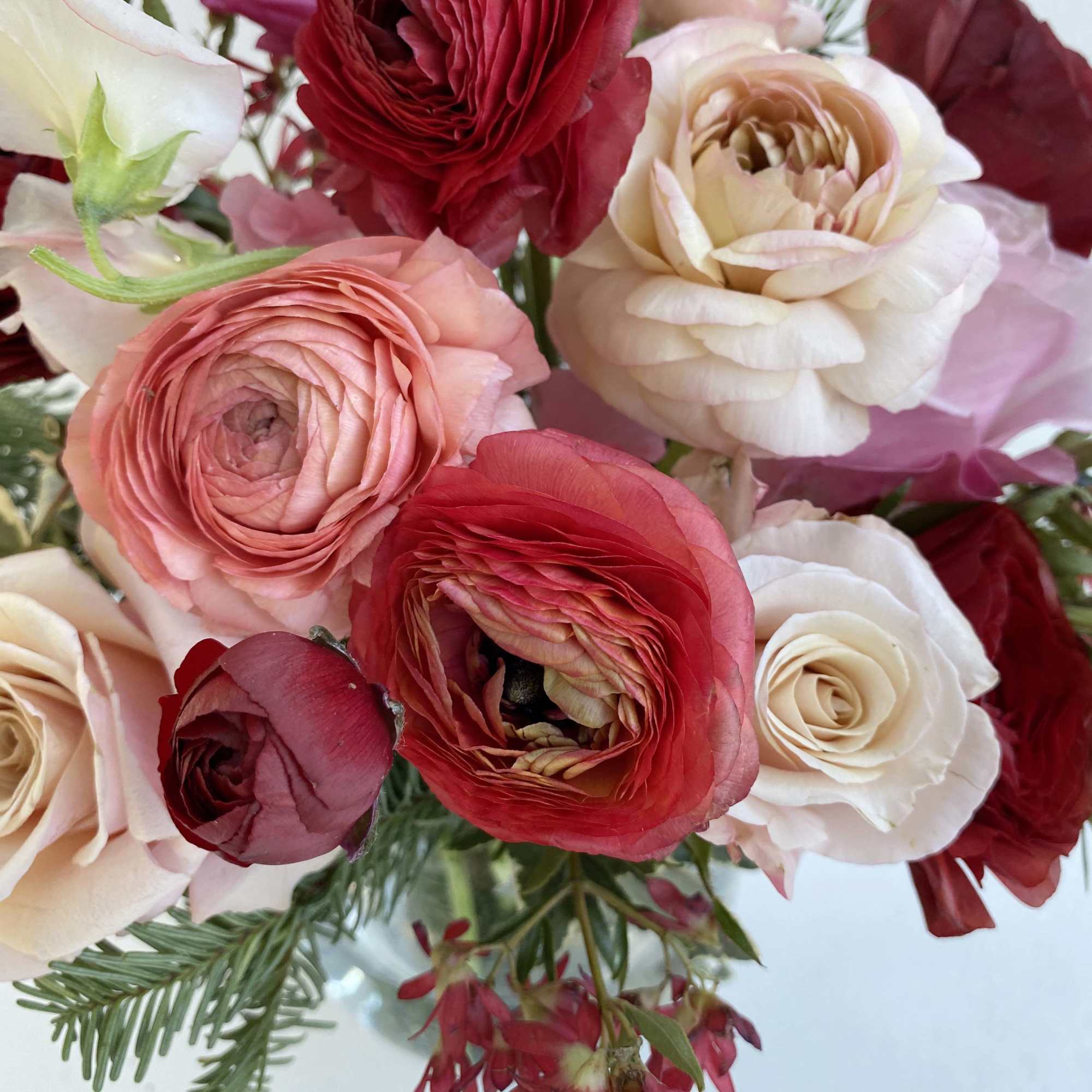 Beautiful warm blushing colors adorn this arrangement of ranunuclus, roses, and seasonal
