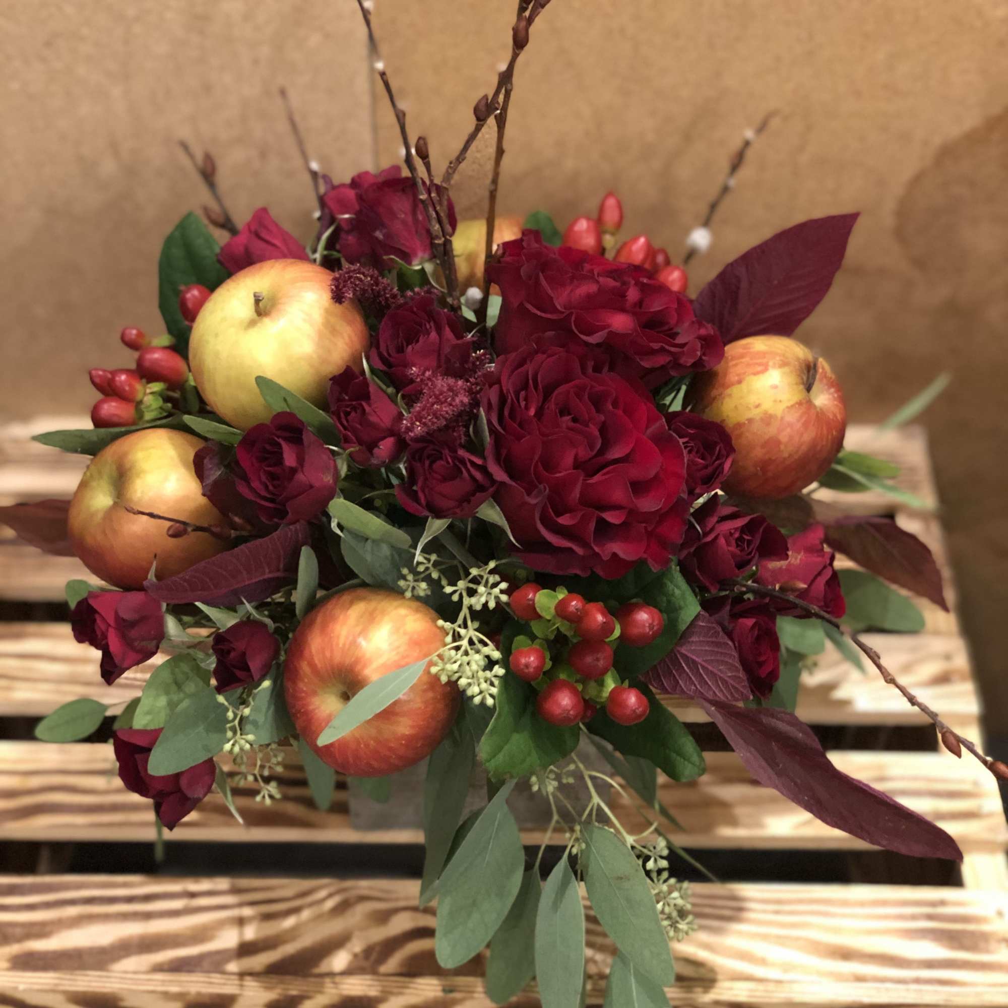 A seasonal display of fresh fall inspired blooms, adorned with crisp red