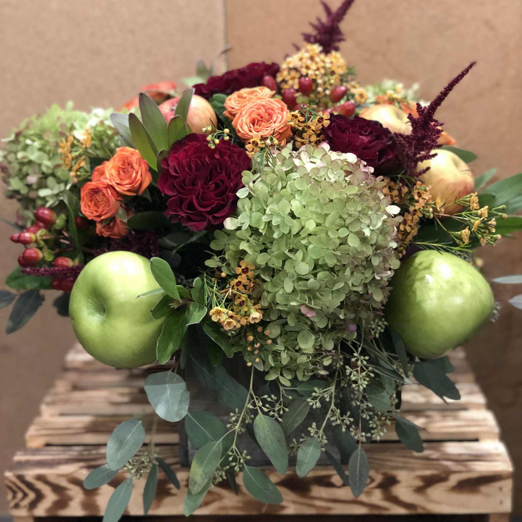A seasonal display of fresh fall inspired blooms, adorned with crisp red