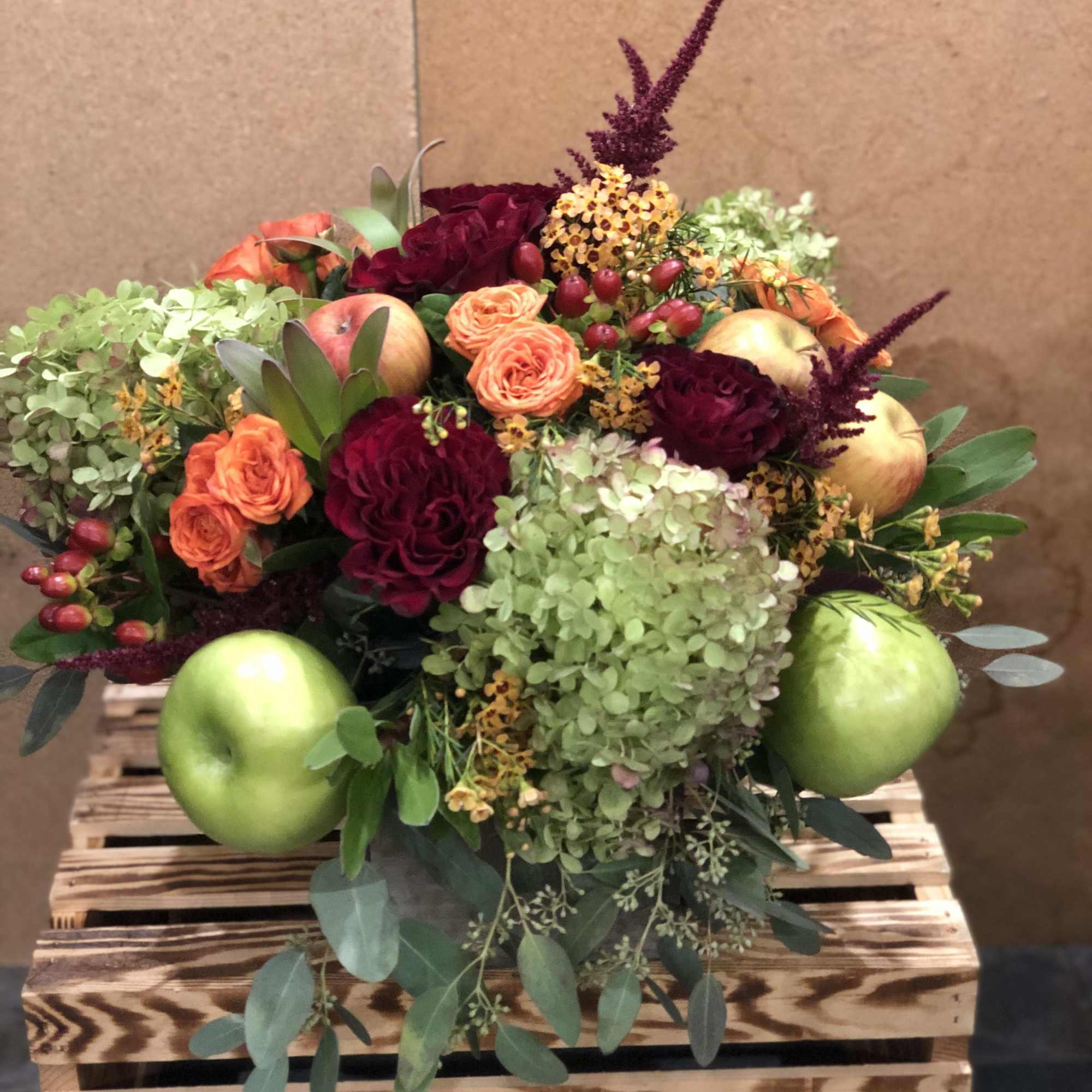 A seasonal display of fresh fall inspired blooms, adorned with crisp red
