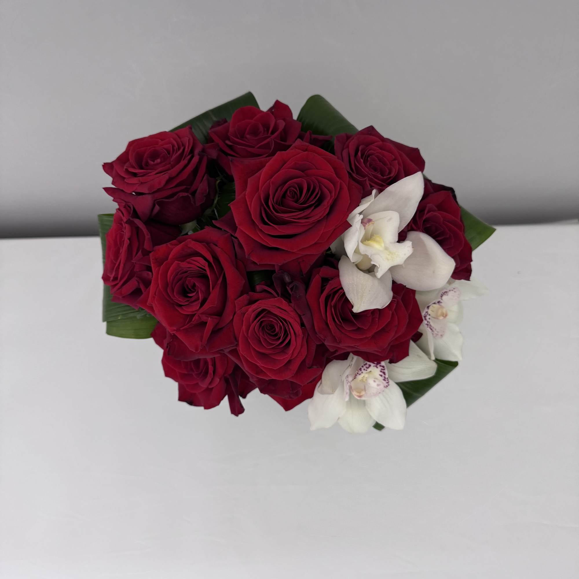 RED LUXE IS AN ARRANGEMENT OF RED ROSES AND CYMBIDUM ORCHIDS DESIGNED