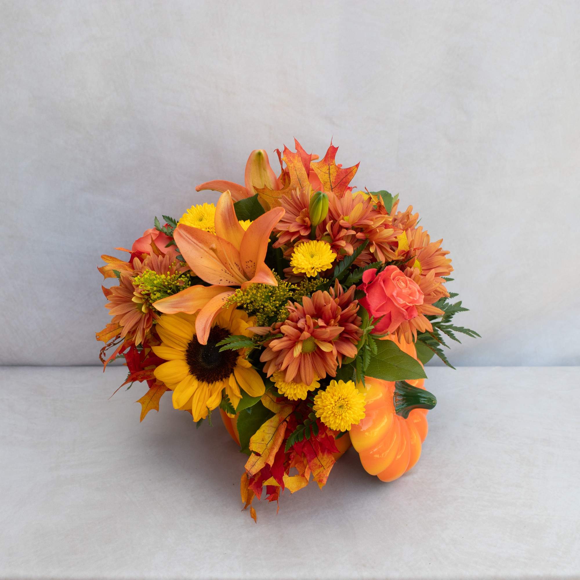 A fall assortment of orange, yellows, and rust flowers like lilies, roses
