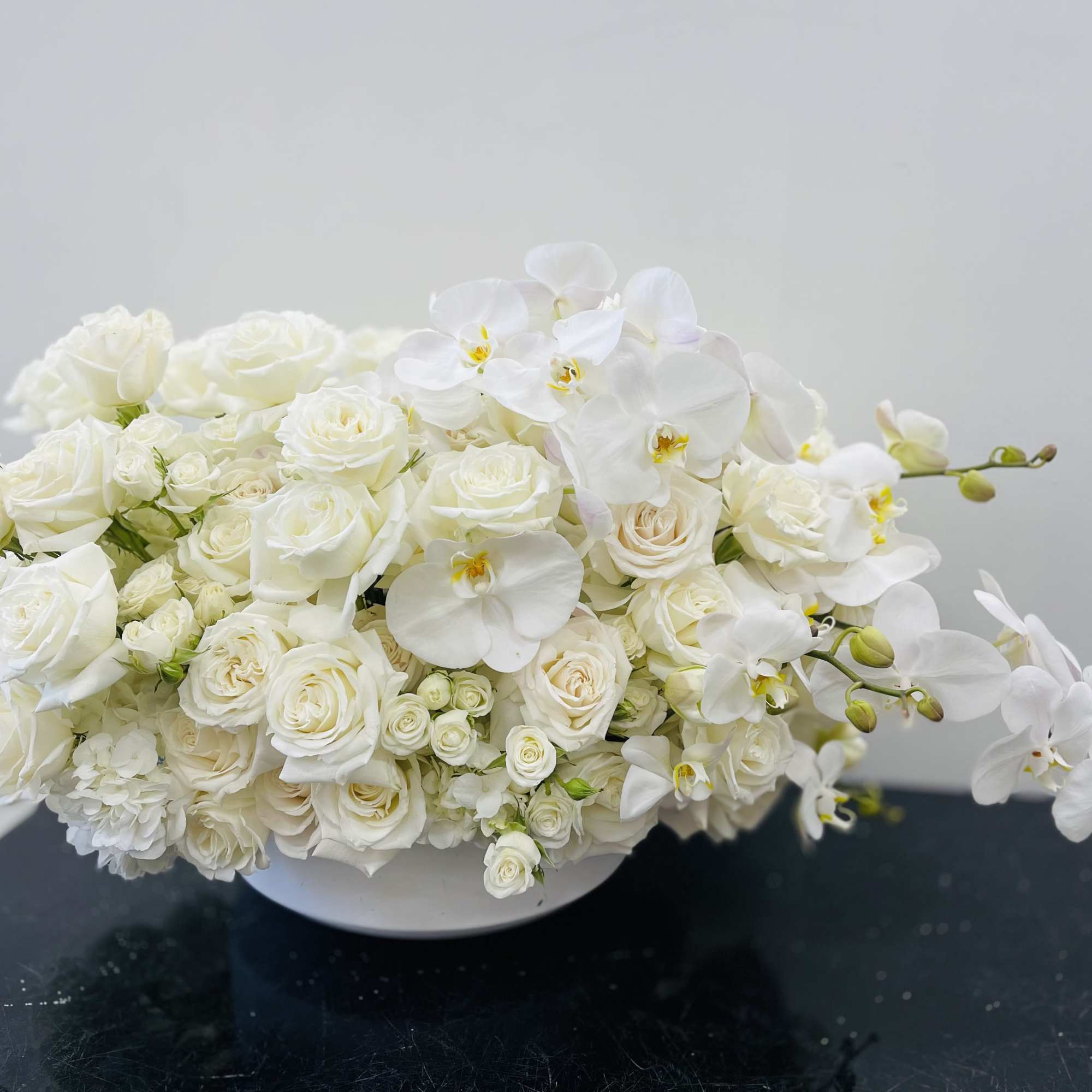 An opulent design featuring lush, full white roses and spray roses, paired