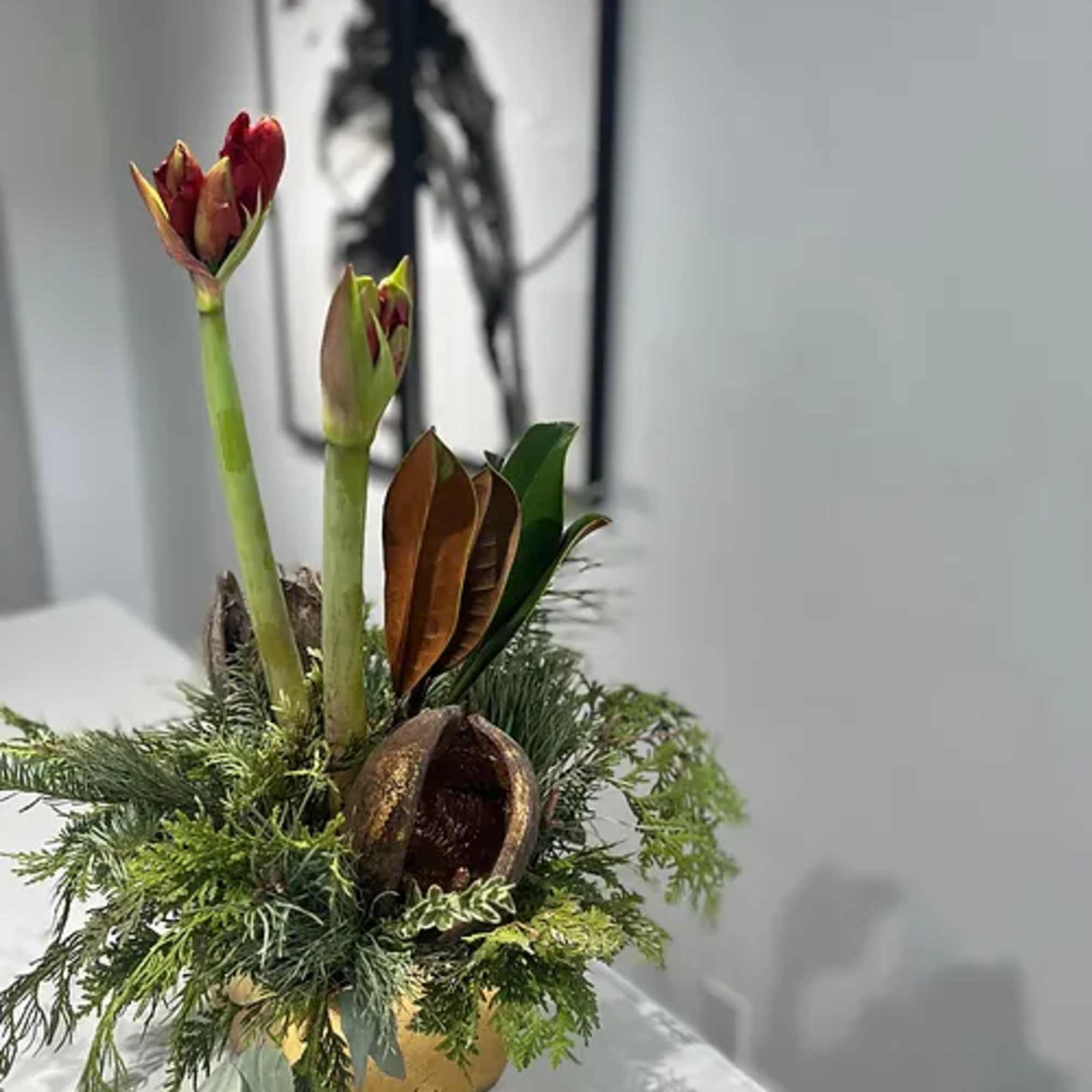 Gold ceramic pot dressed with fragrant holiday greens wrapped around a single