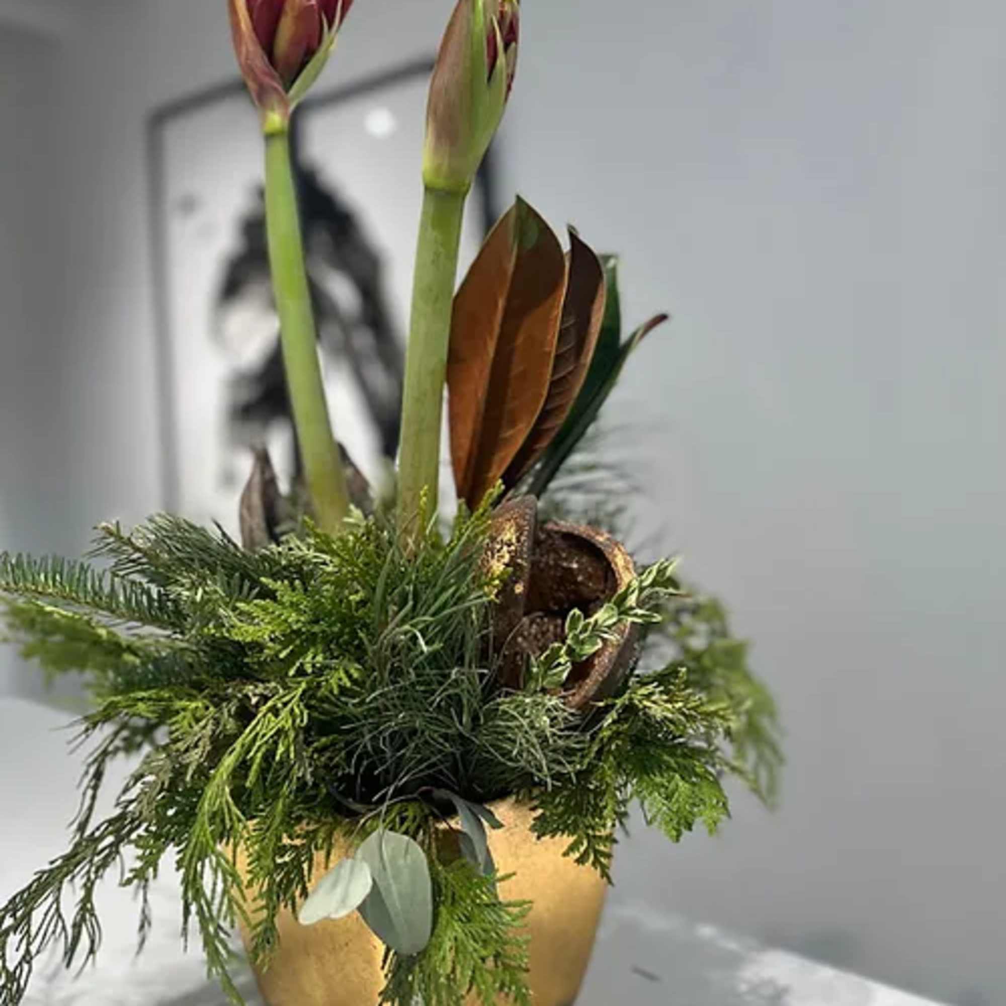 Gold ceramic pot dressed with fragrant holiday greens wrapped around a single