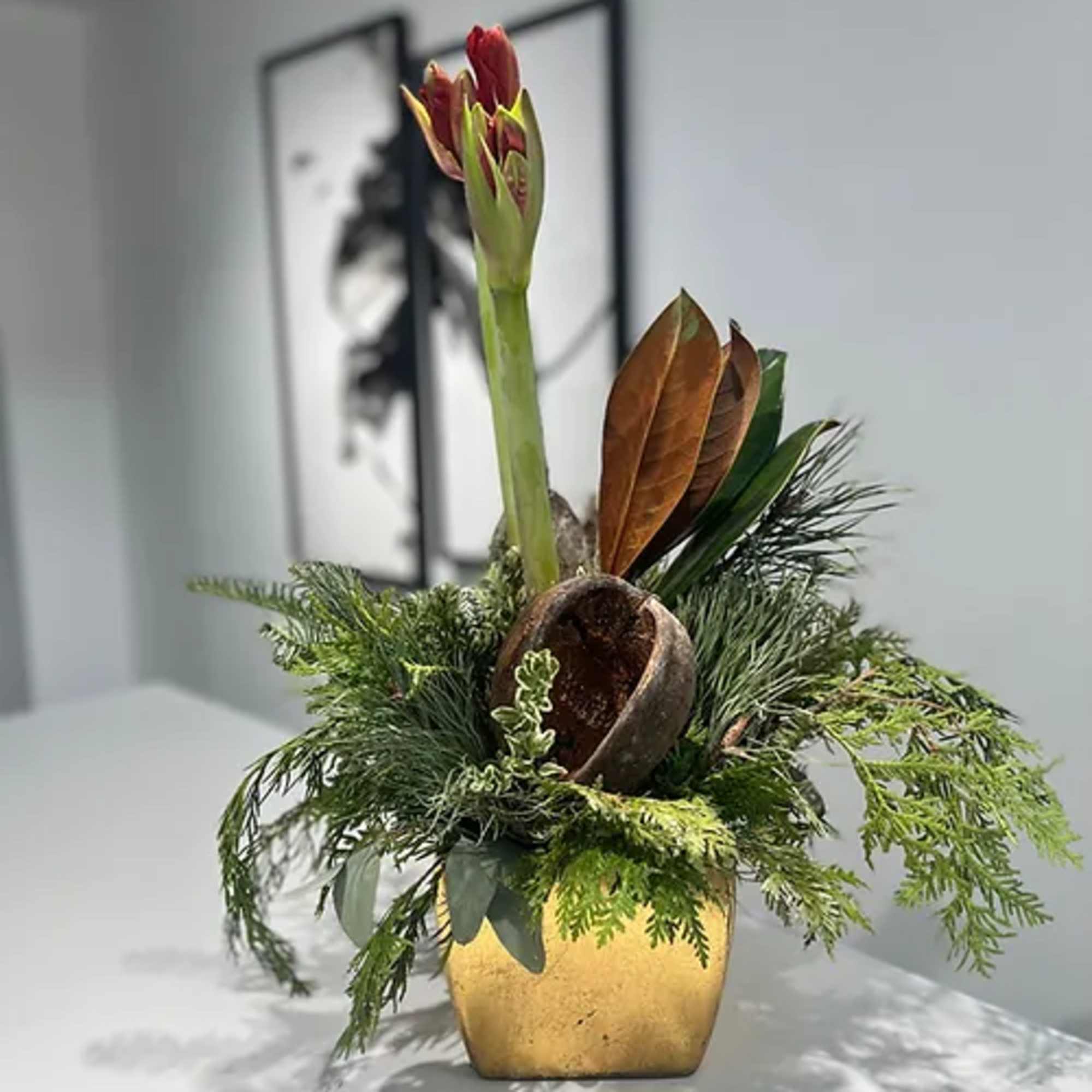 Gold ceramic pot dressed with fragrant holiday greens wrapped around a single