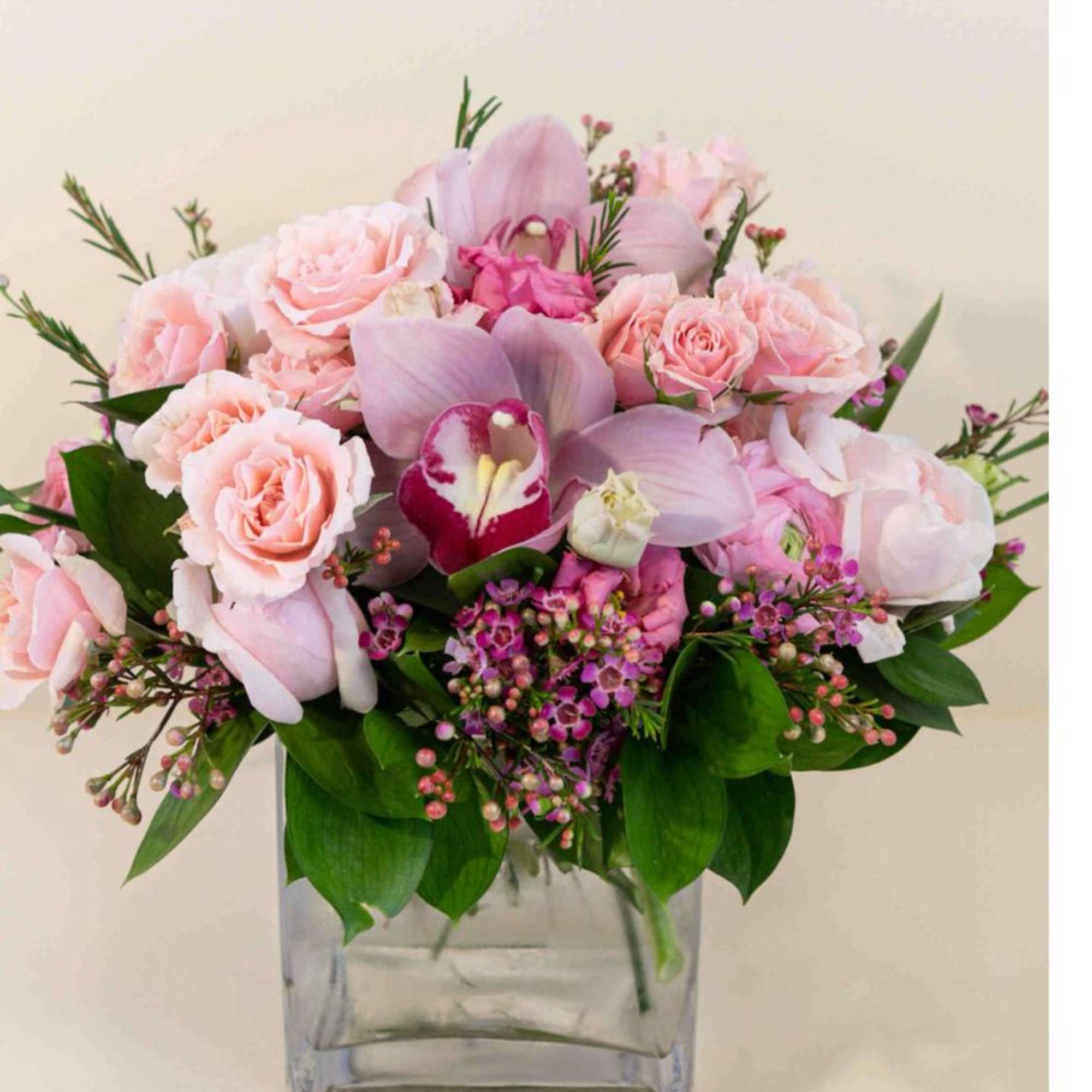 This beautiful creation of pink roses, cymbidium in a square vase is