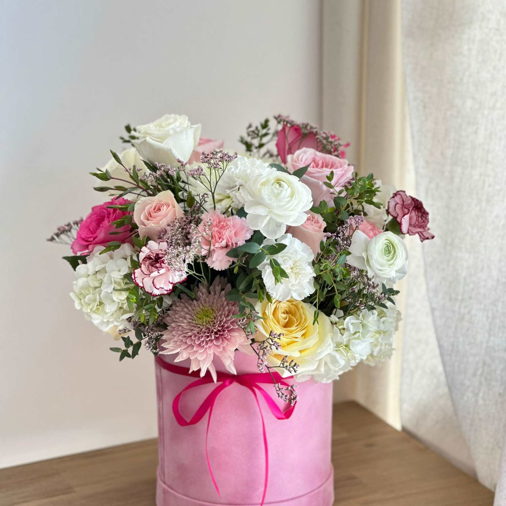 A tall, round pink velvet box filled with pink, light pink, and