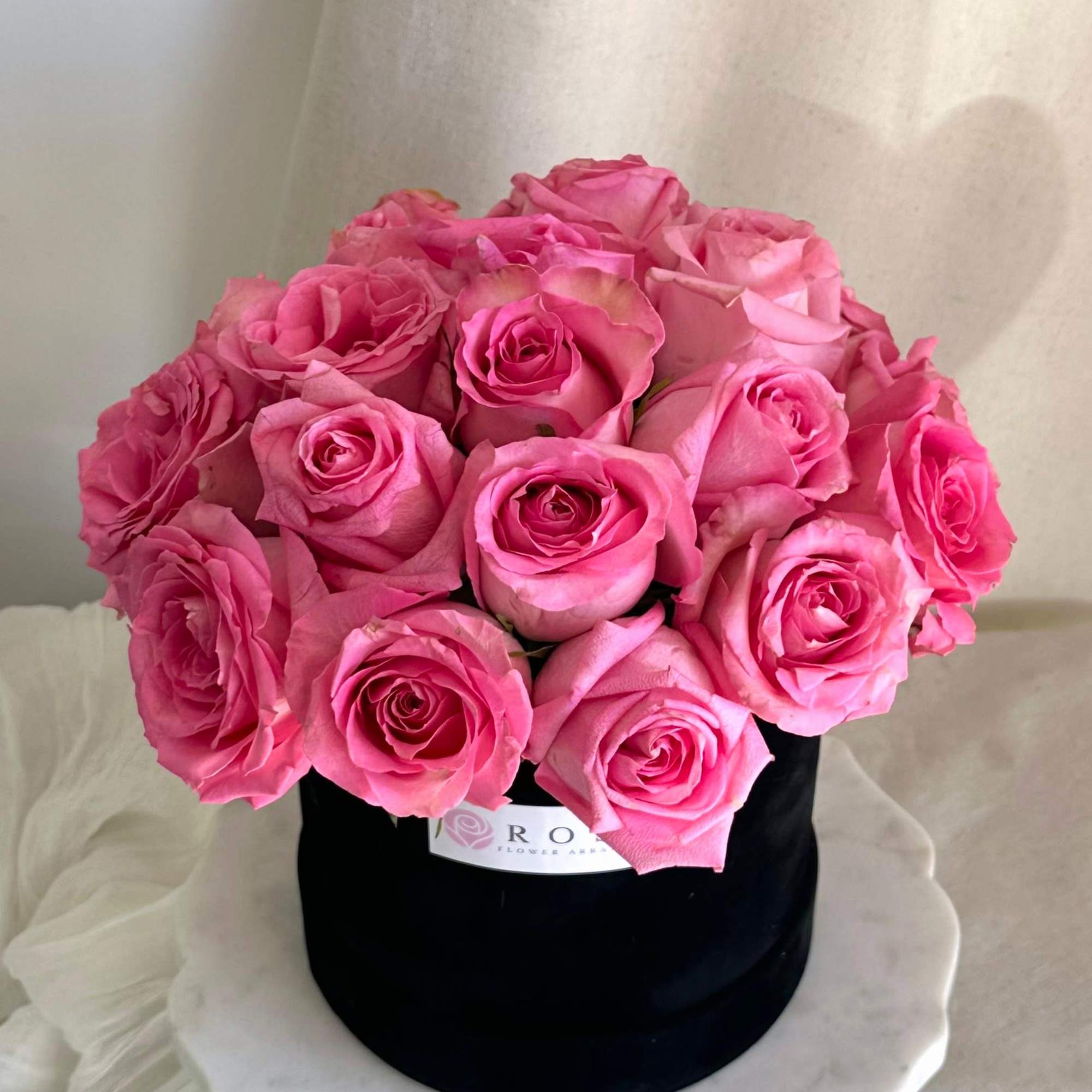 A medium round black velvet box with roses arranged in a dome A medium round black velvet box with roses arranged in a dome