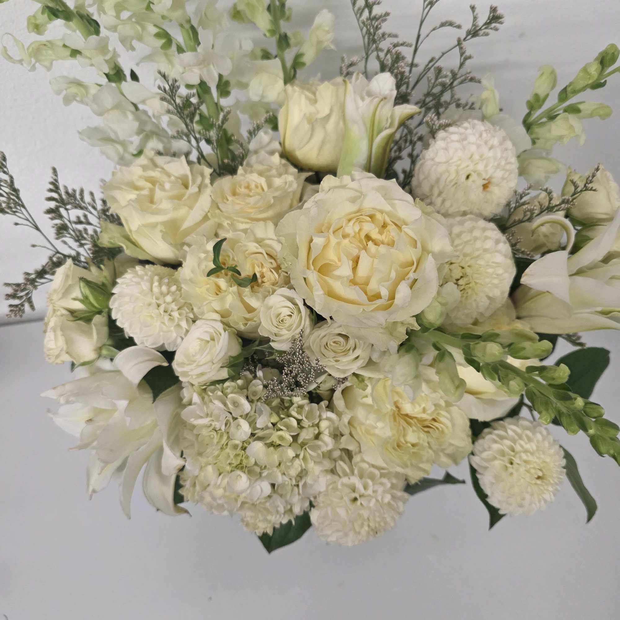 A beautiful arrangement of white garden roses, lilies, snap dragons and other