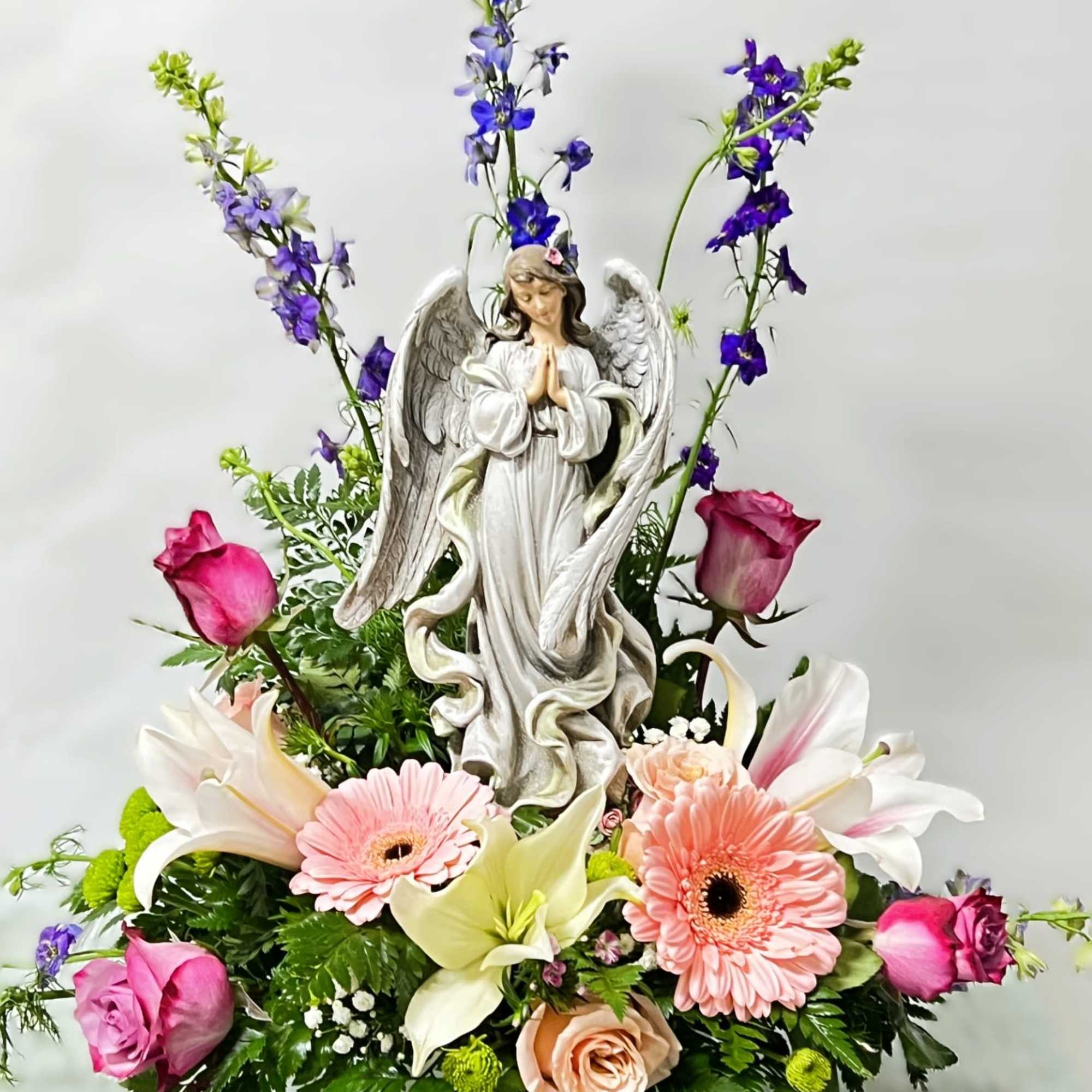 An arrangement of fresh cut flowers. Arrangement includes a statue that depicts