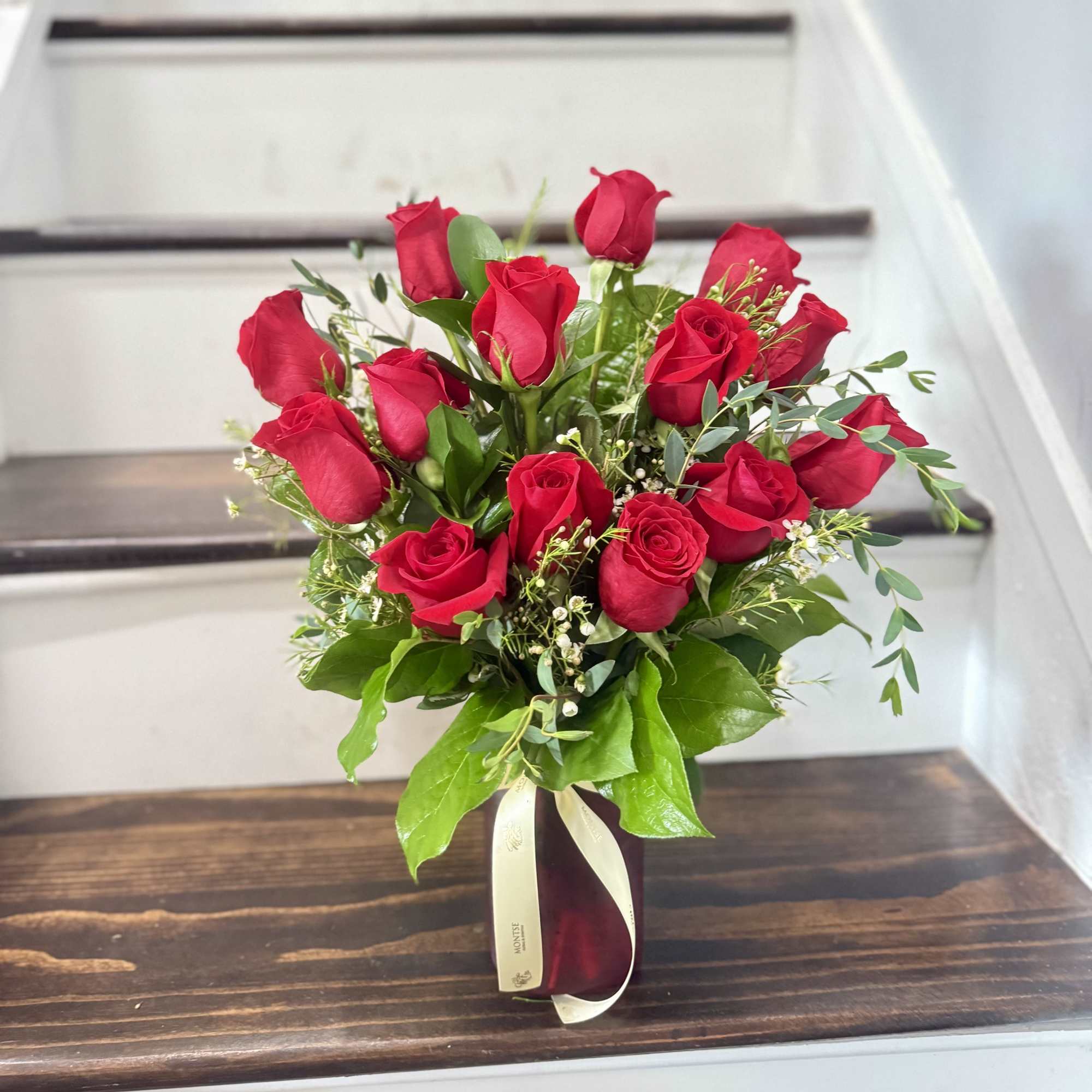 7 red roses in a vase with eucalyptus and wax flowers 