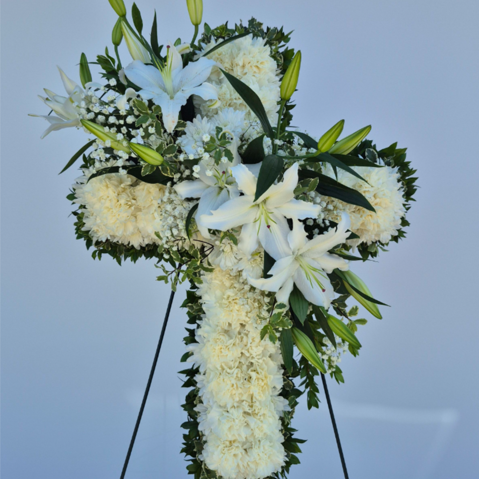 The cross made with beautiful white carnations with bloomed oriental lilies in