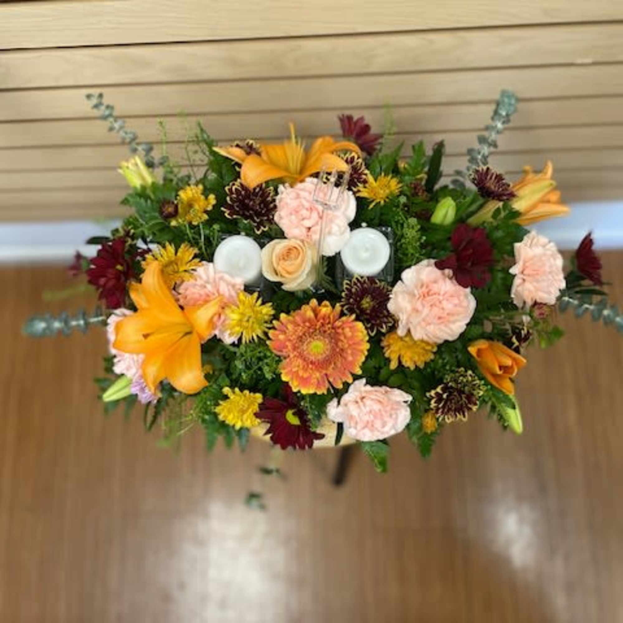 Fall centerpiece with mixed flowers and candles. The arrangement contains orange lilies Fall centerpiece with mixed flowers and candles. The arrangement contains orange lilies