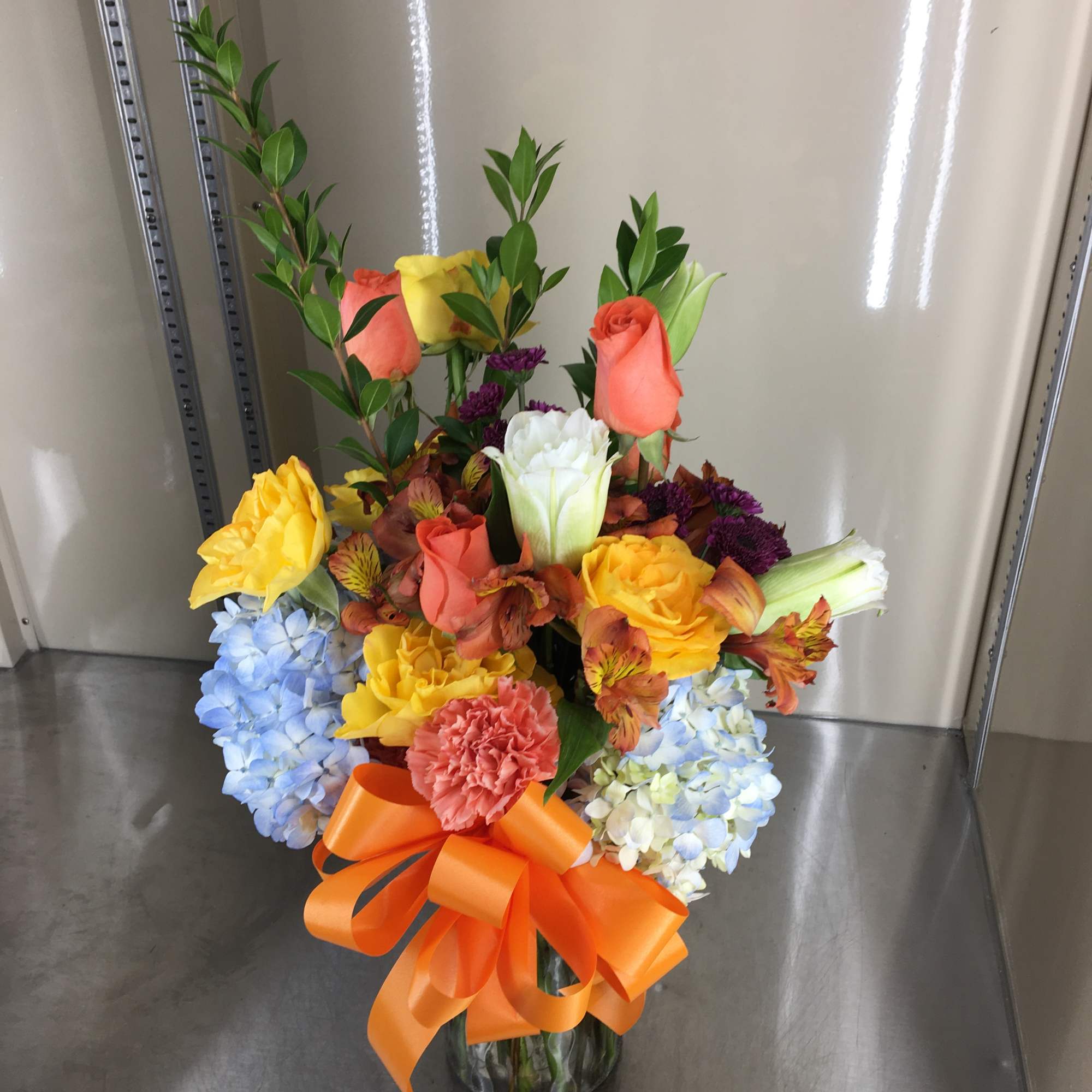 Mixed cut arrangement with yellow roses, blue hydrangea, orange alstroemeria, salmon roses Mixed cut arrangement with yellow roses, blue hydrangea, orange alstroemeria, salmon roses