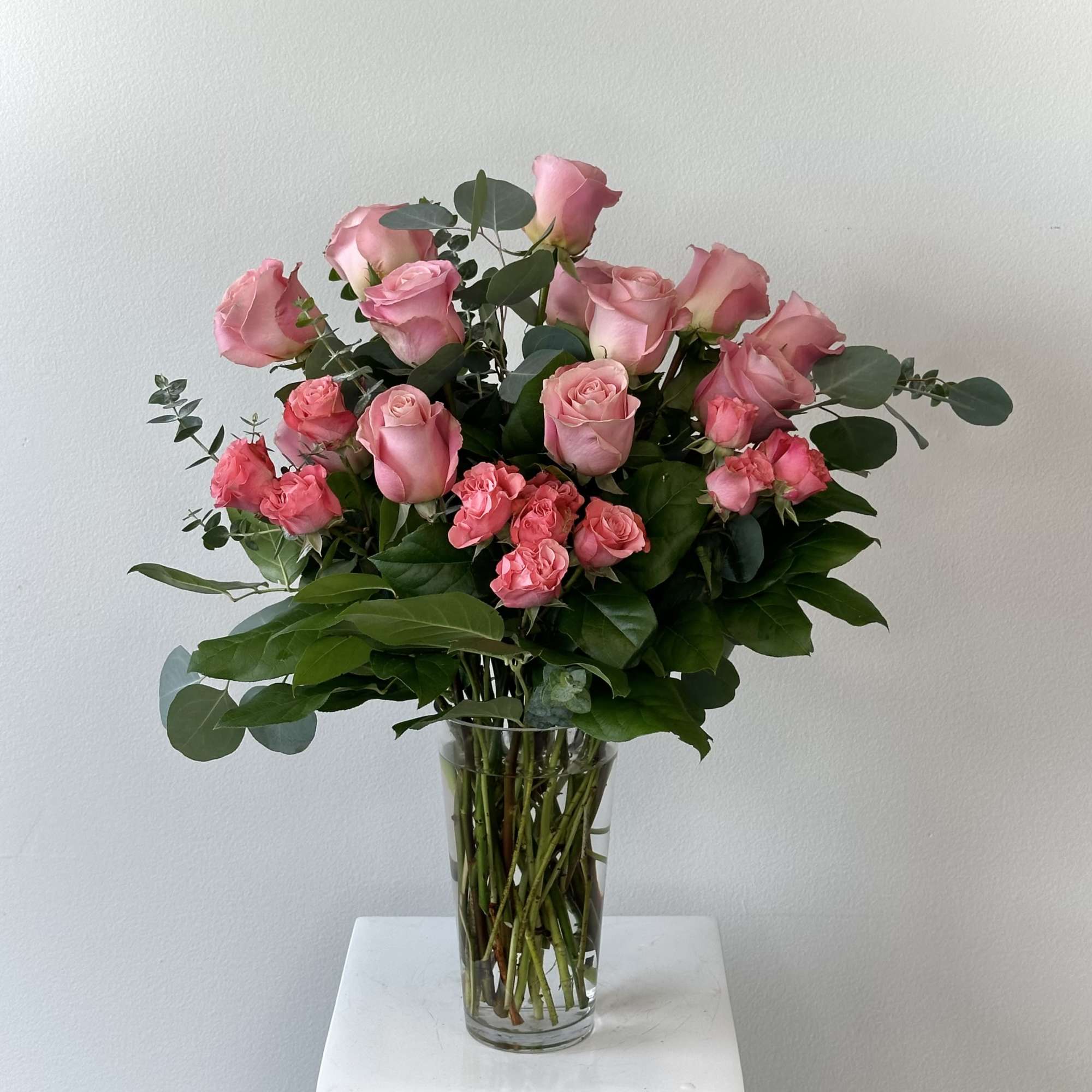 This arrangement is one dozen premium pink roses with greenery added to
