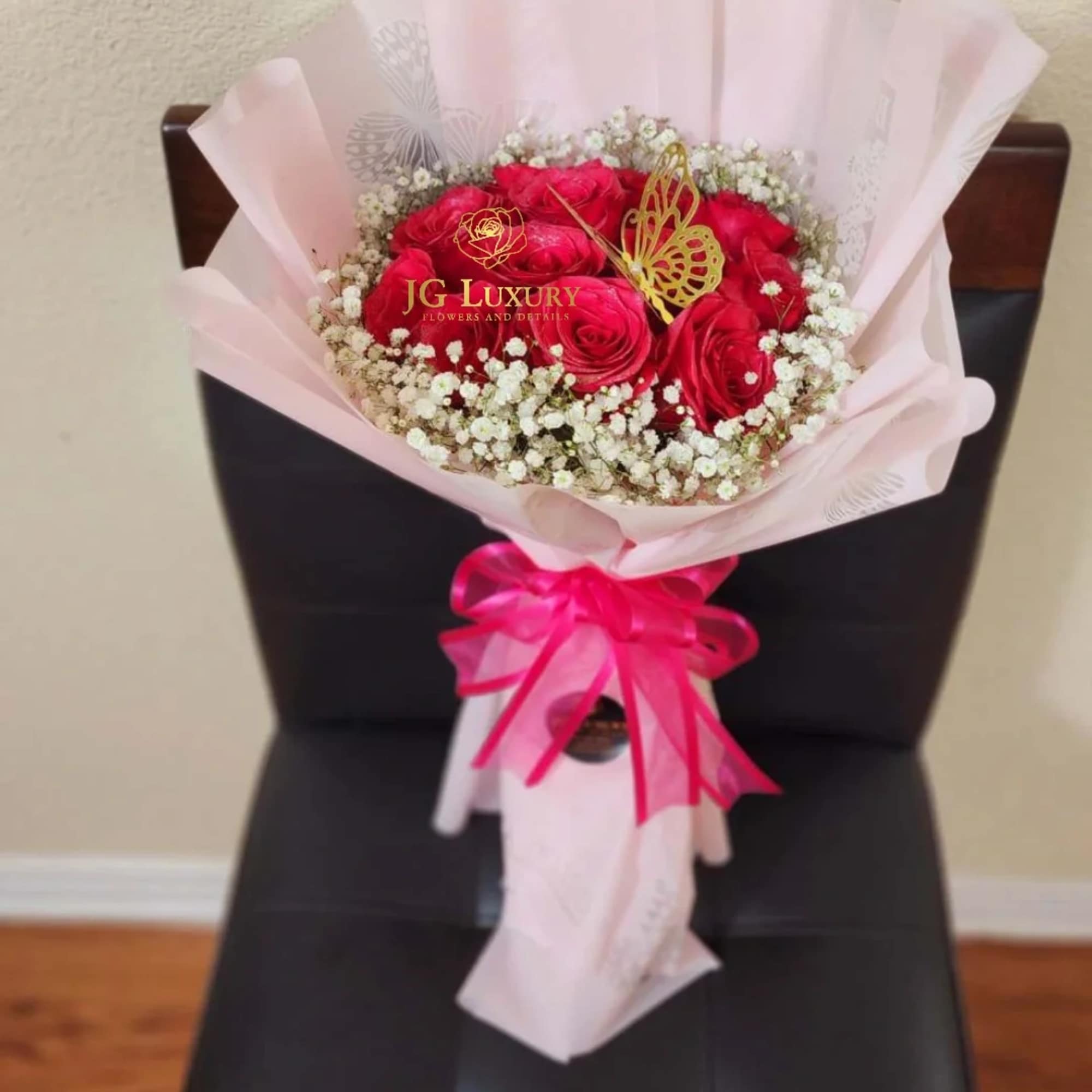 A dozen hot pink premium roses surrounded by baby&#039;s breath tied tight