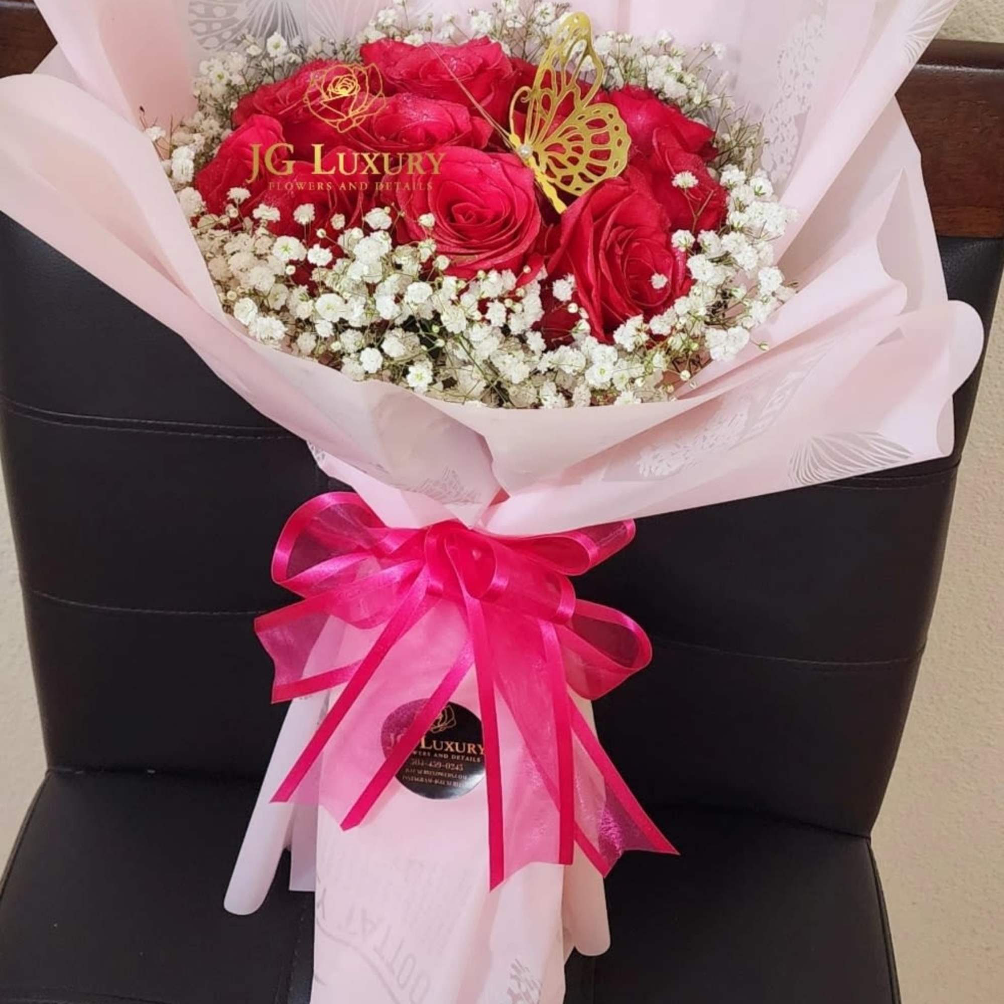 A dozen hot pink premium roses surrounded by baby&#039;s breath tied tight