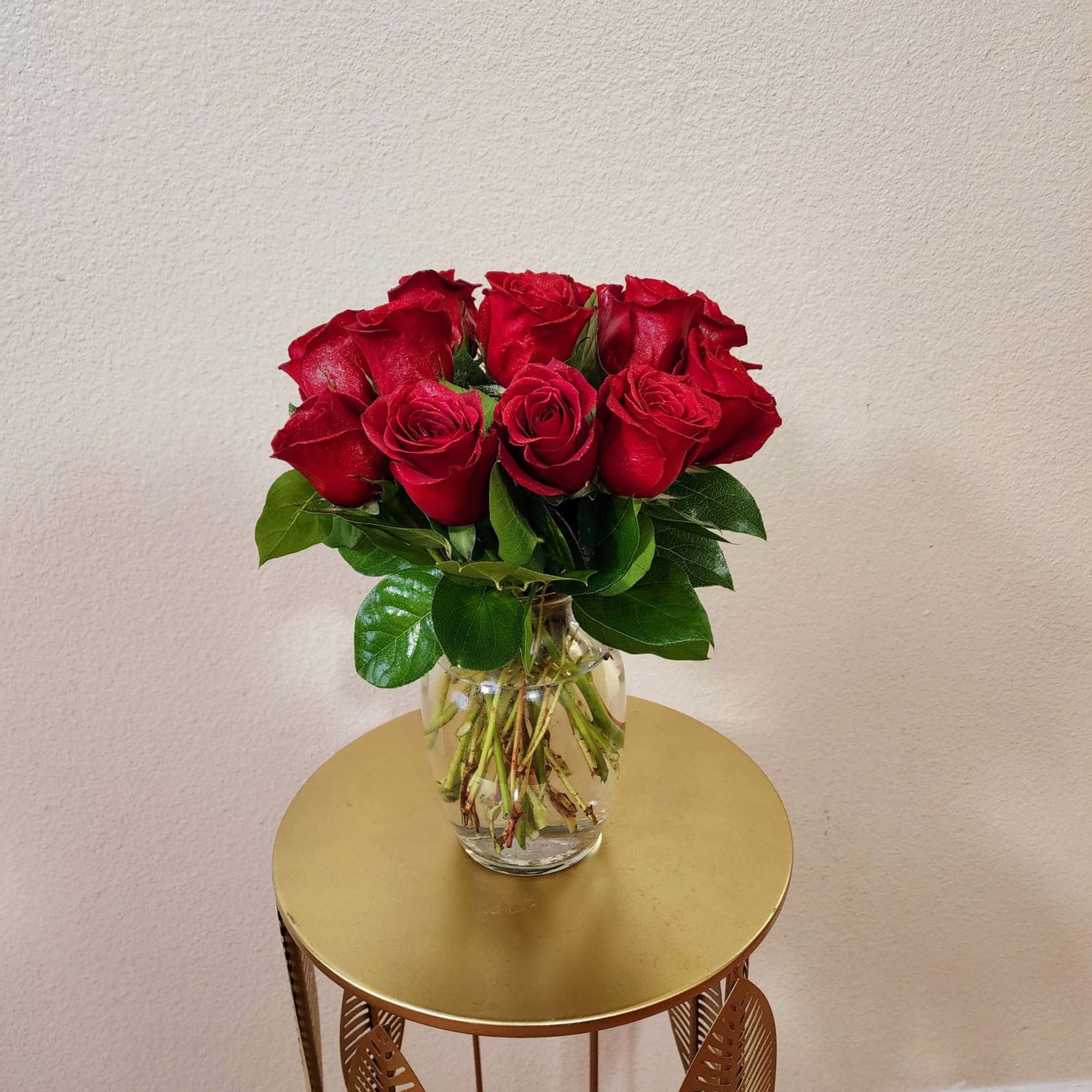 Roses in a clear vase with some greens in it, a classic