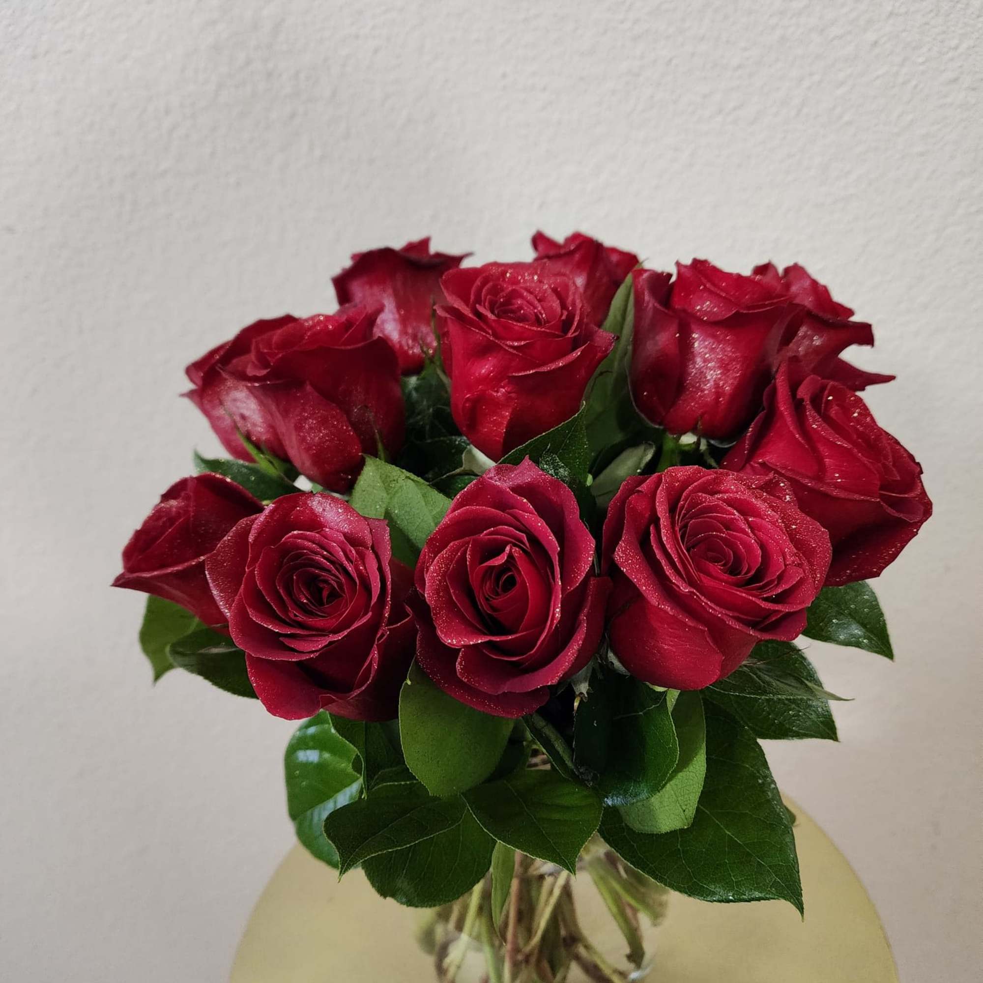 Roses in a clear vase with some greens in it, a classic