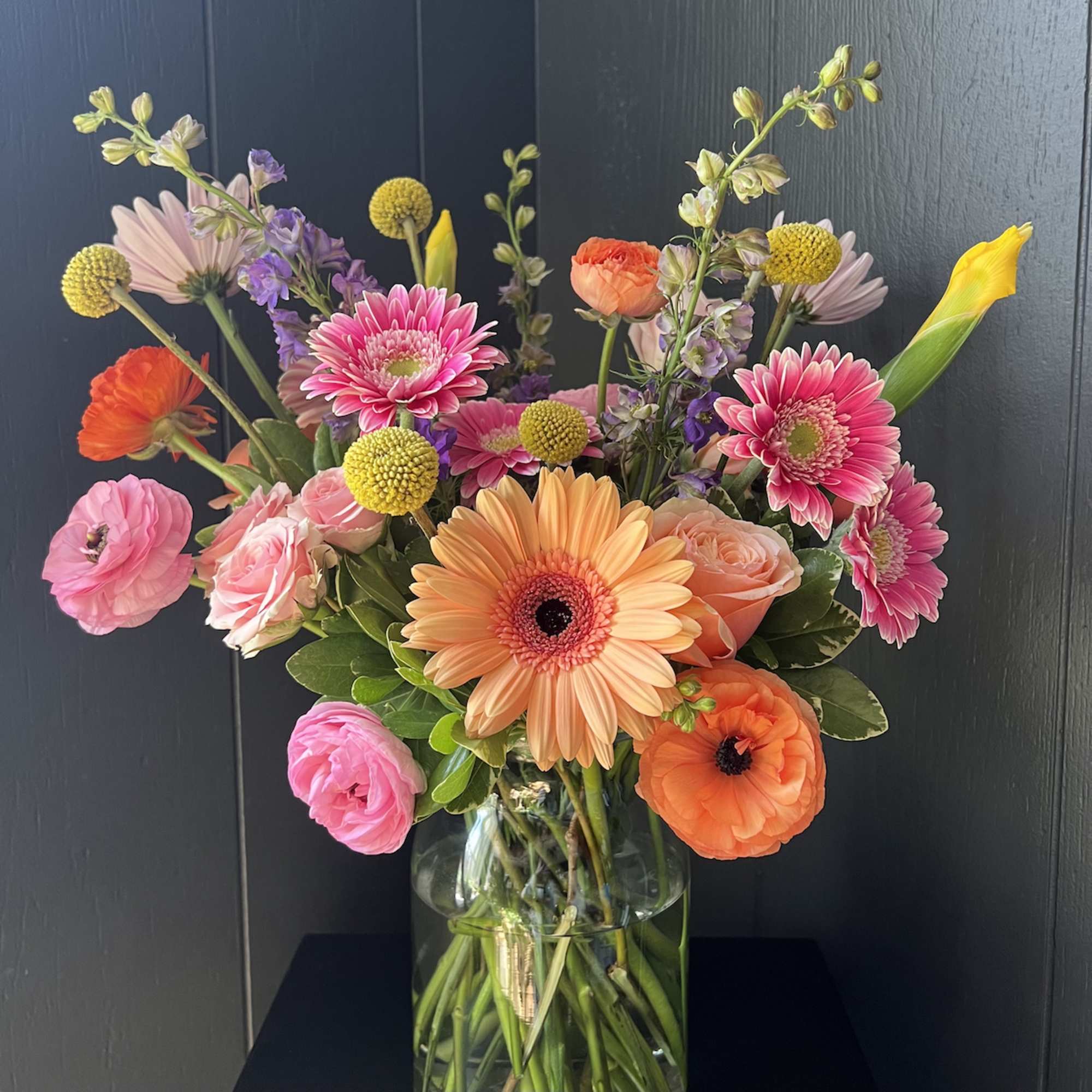 Seasonal, colorful flowers and foliage artfully arranged in a clear glass vase.

Year