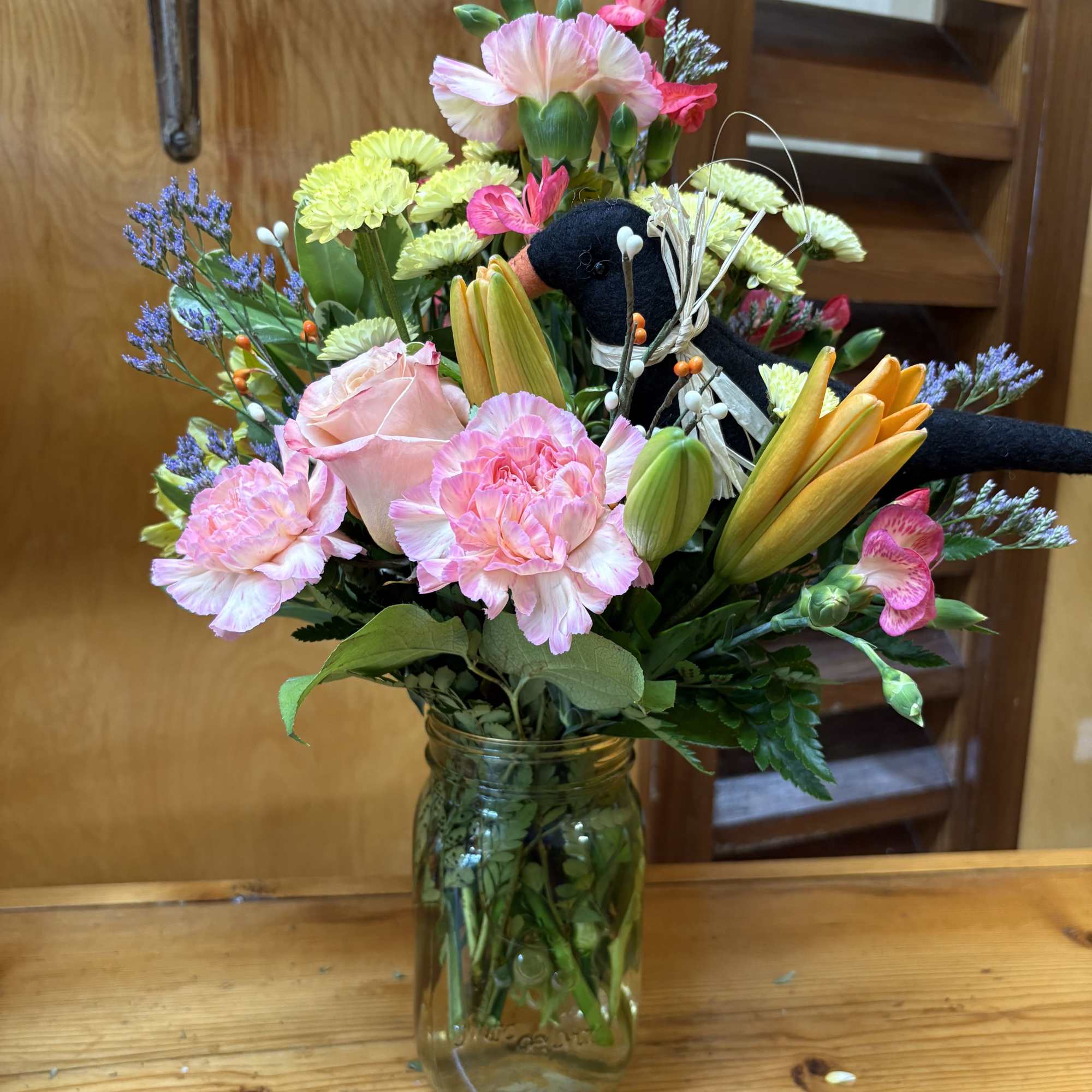 A mixed autumn hued arrangement in a yellow glass vase with a