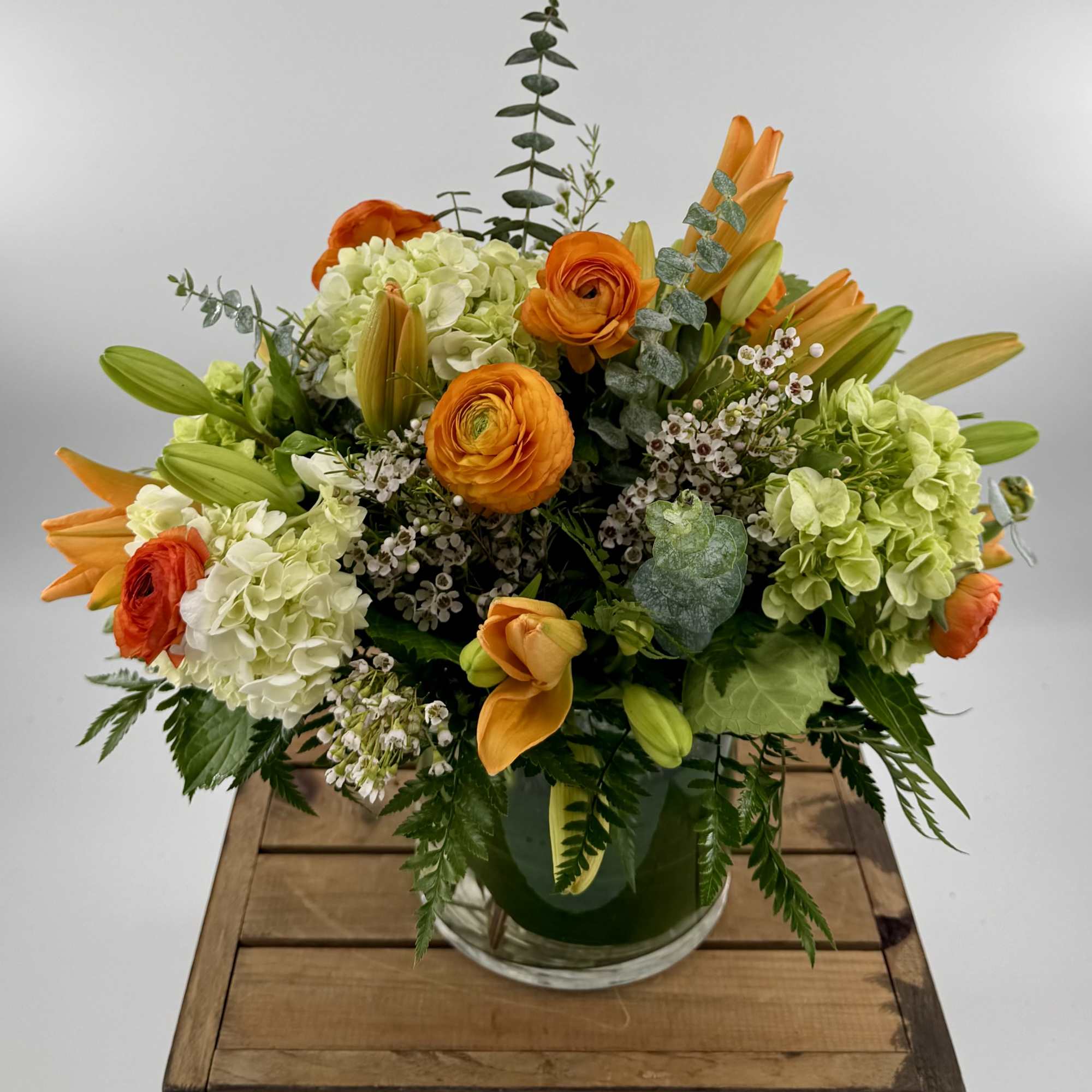 A Stunning Floral Arrangement with orange ranunculus, orange Lilies, green mini Hydrangea