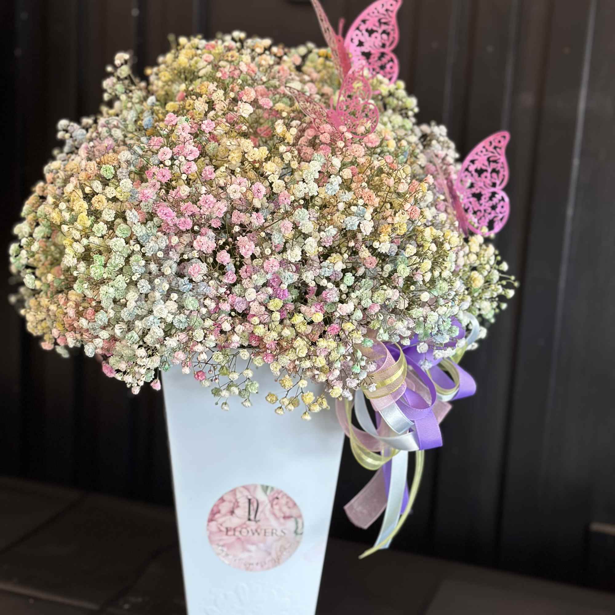 A tall arrangement filled with a bright colorful baby's breath wrapped in A tall arrangement filled with a bright colorful baby's breath wrapped in