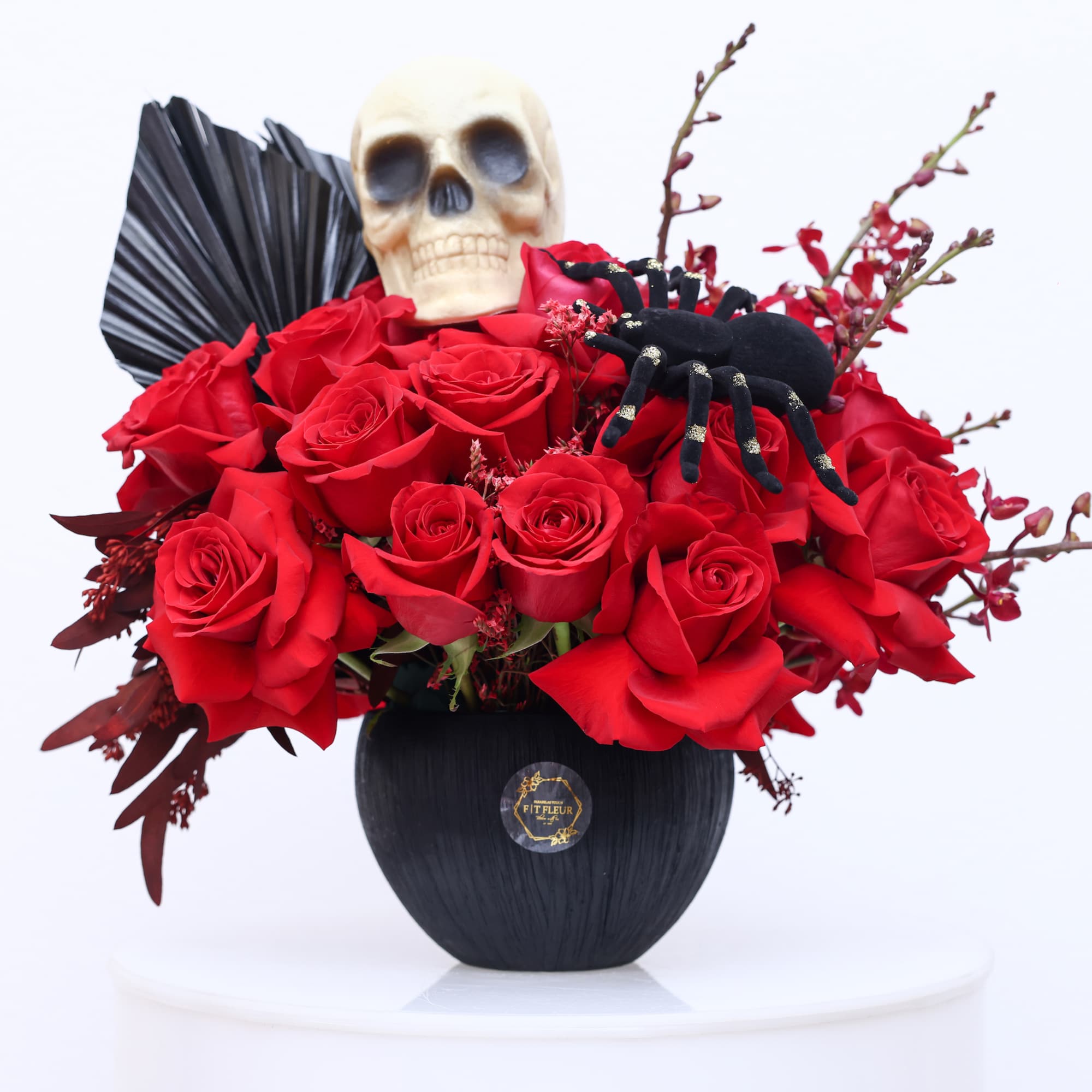 Halloween inspired arrangement designed with red roses, red yucca seeds and perserved
