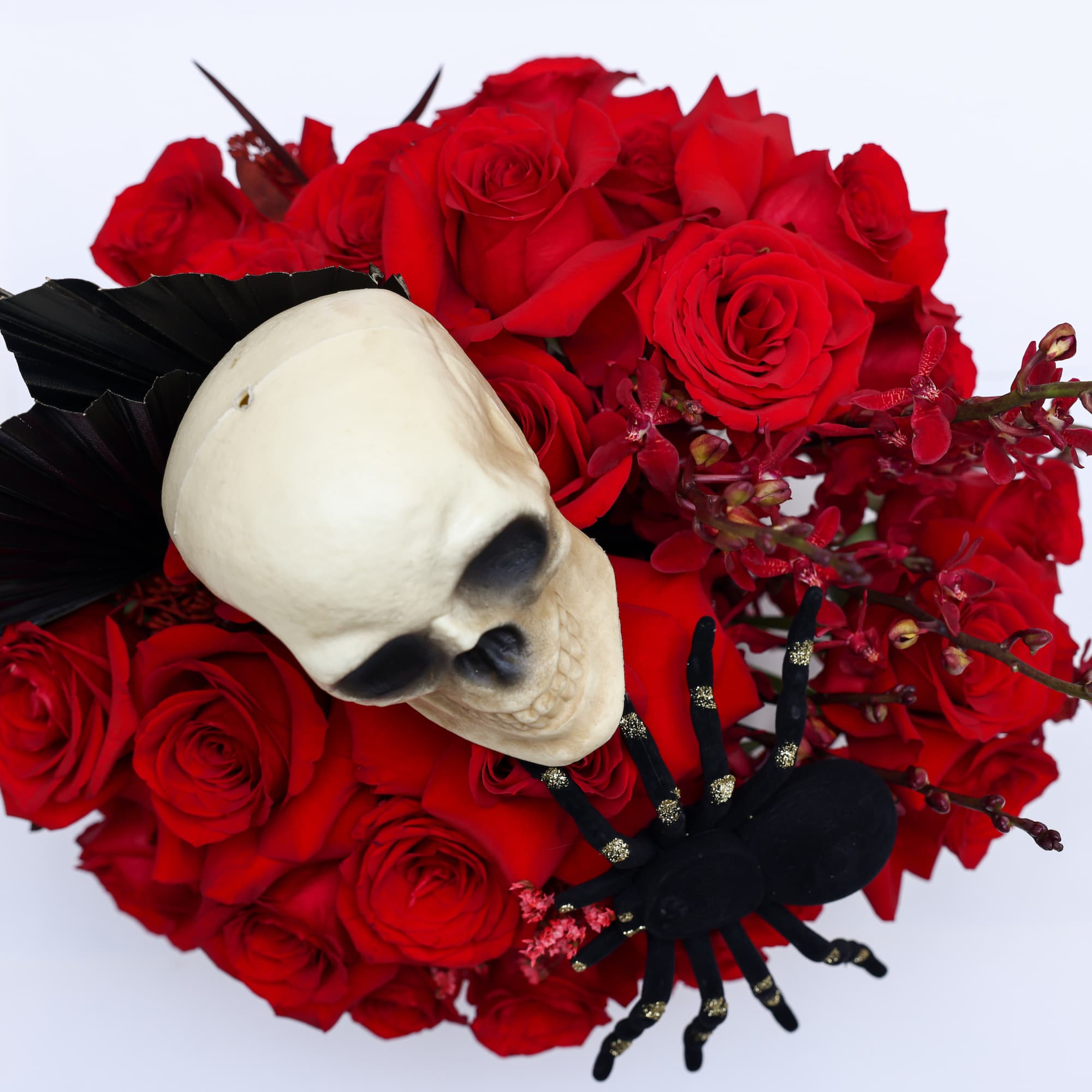 Halloween inspired arrangement designed with red roses, red yucca seeds and perserved