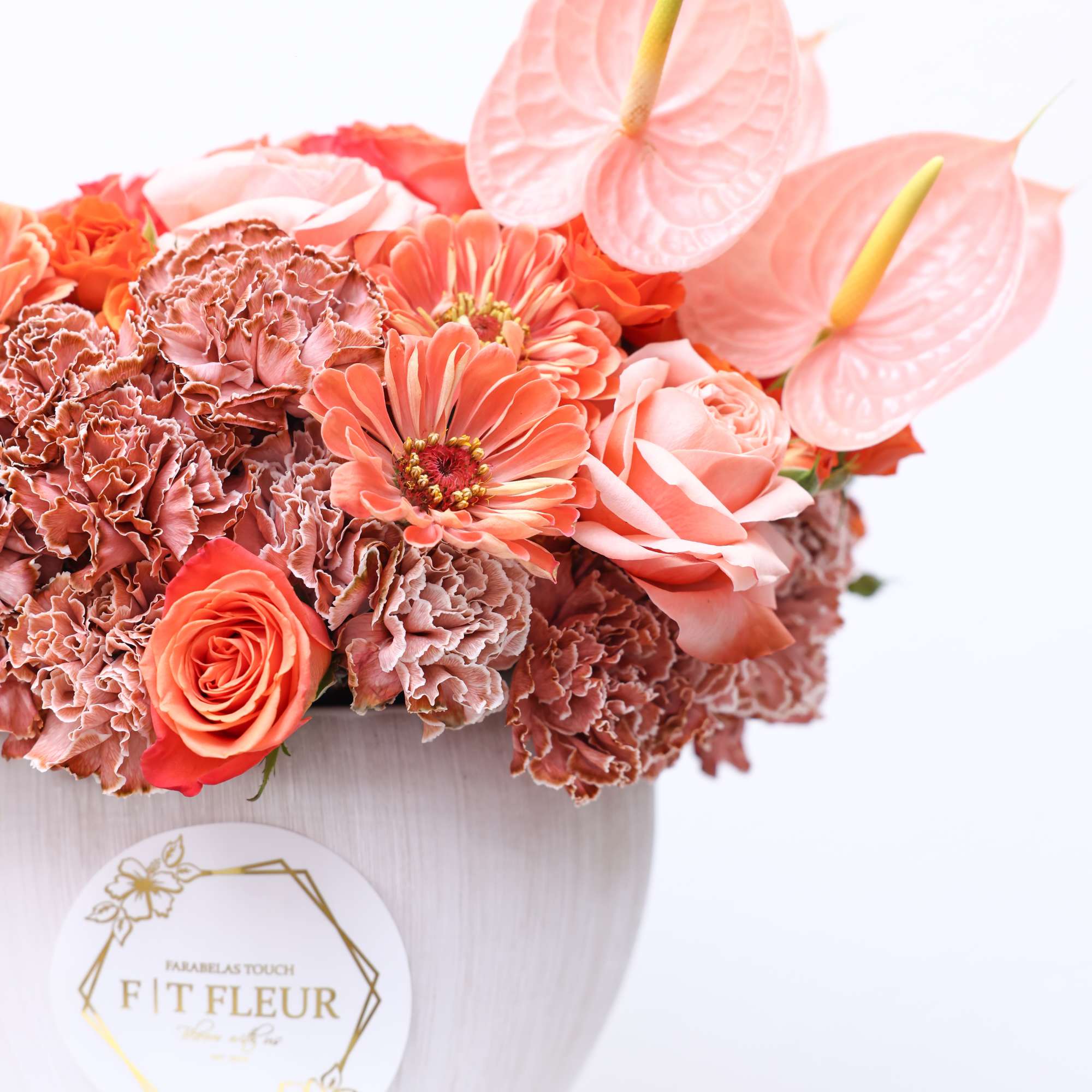 This arrangement is a peach combo of florals on a white vase.