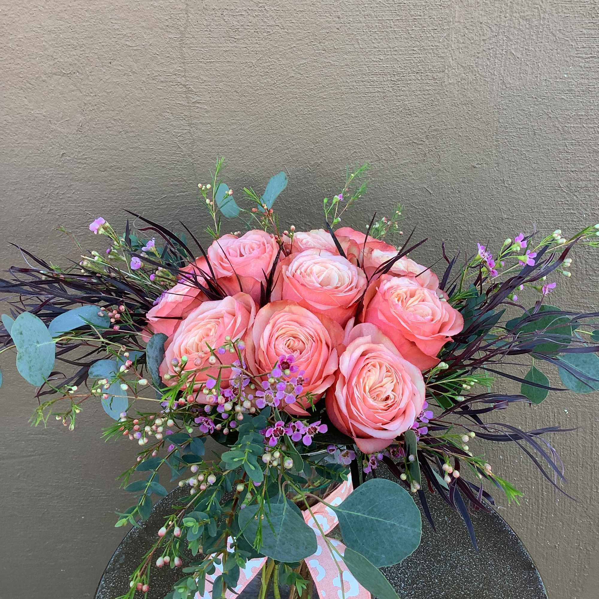 12 beautiful peach/coral/orange roses arranged low and lush.