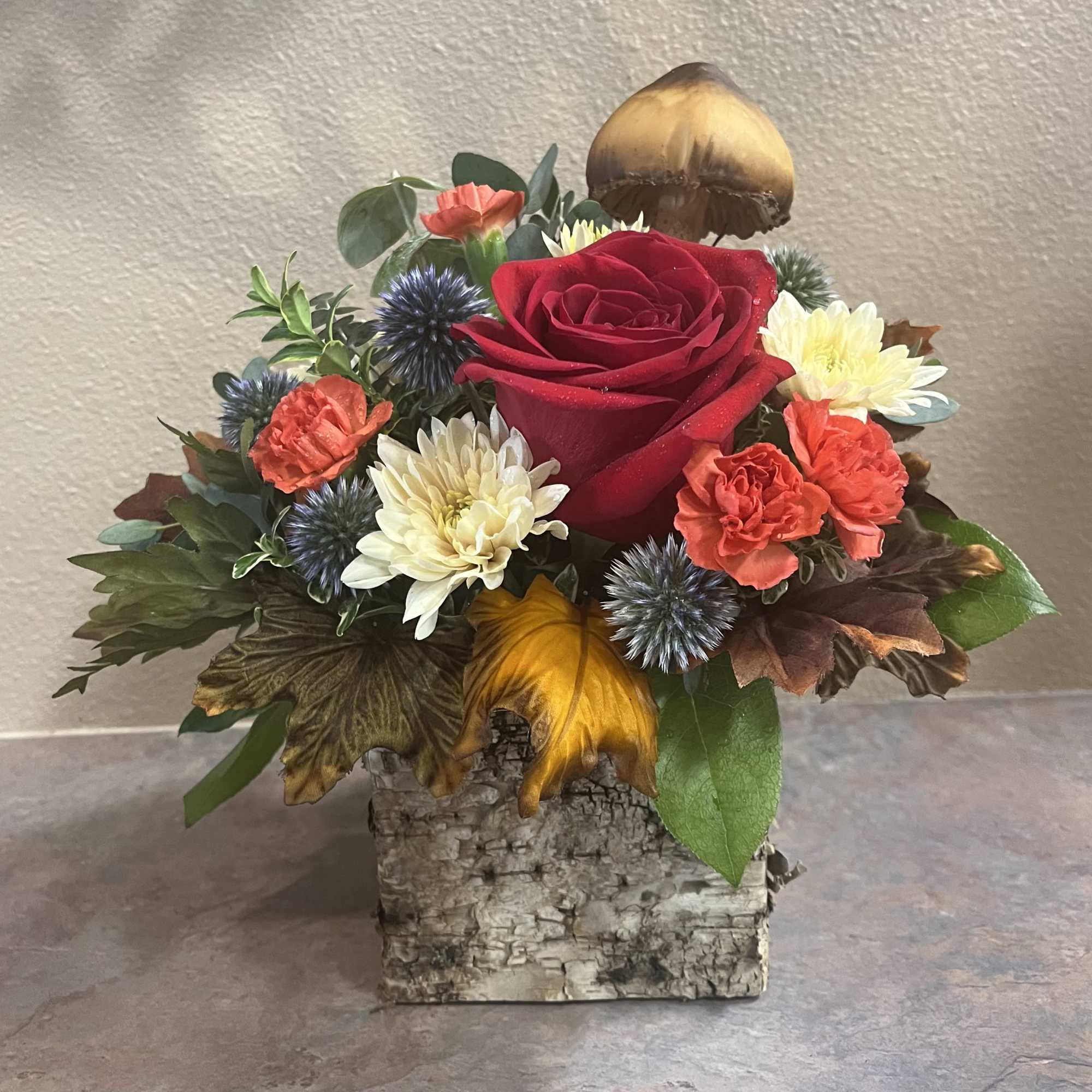 This arrangement is a mix of colorful flowers with a woodsy, natural