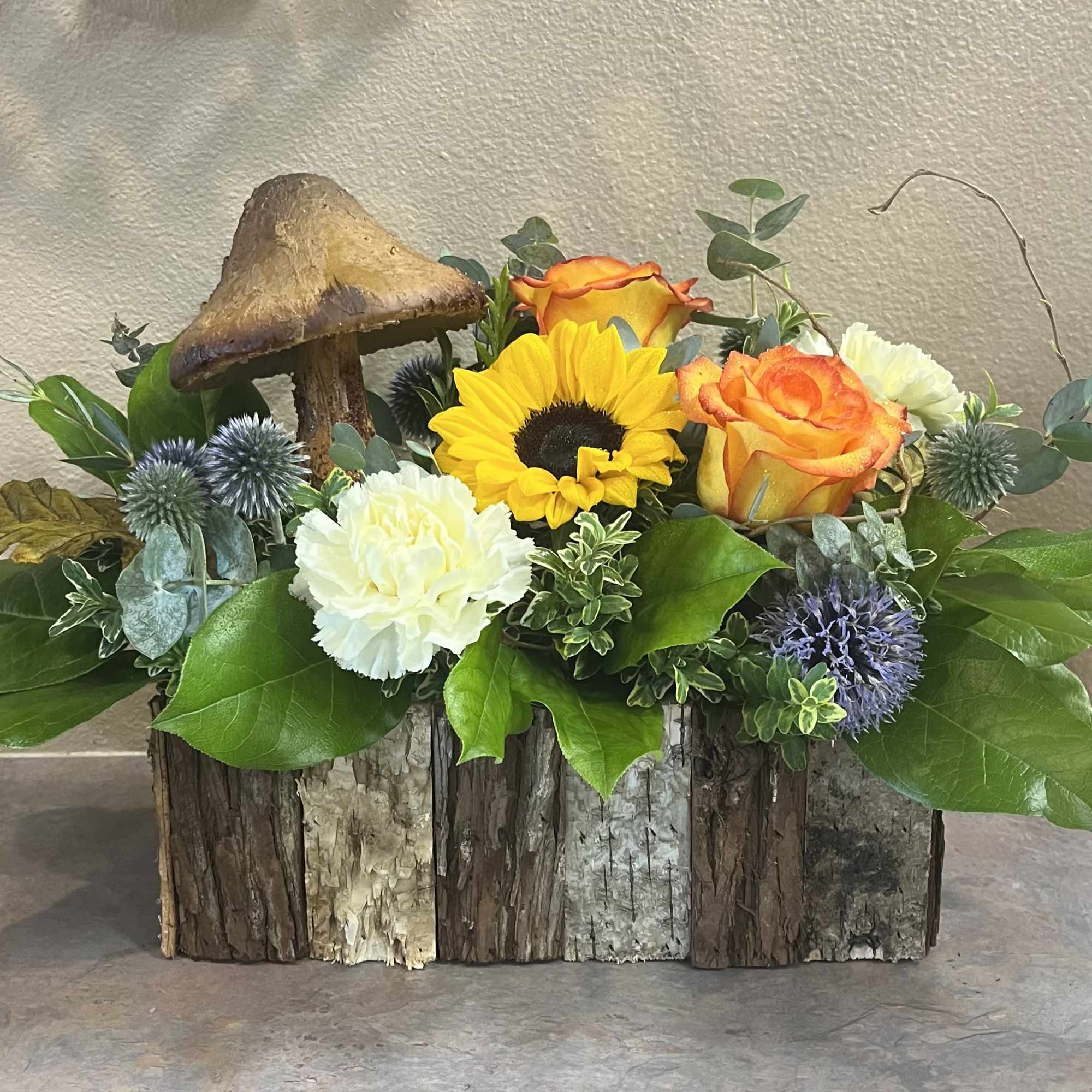 This arrangement is a mix of colorful flowers with a woodsy, natural