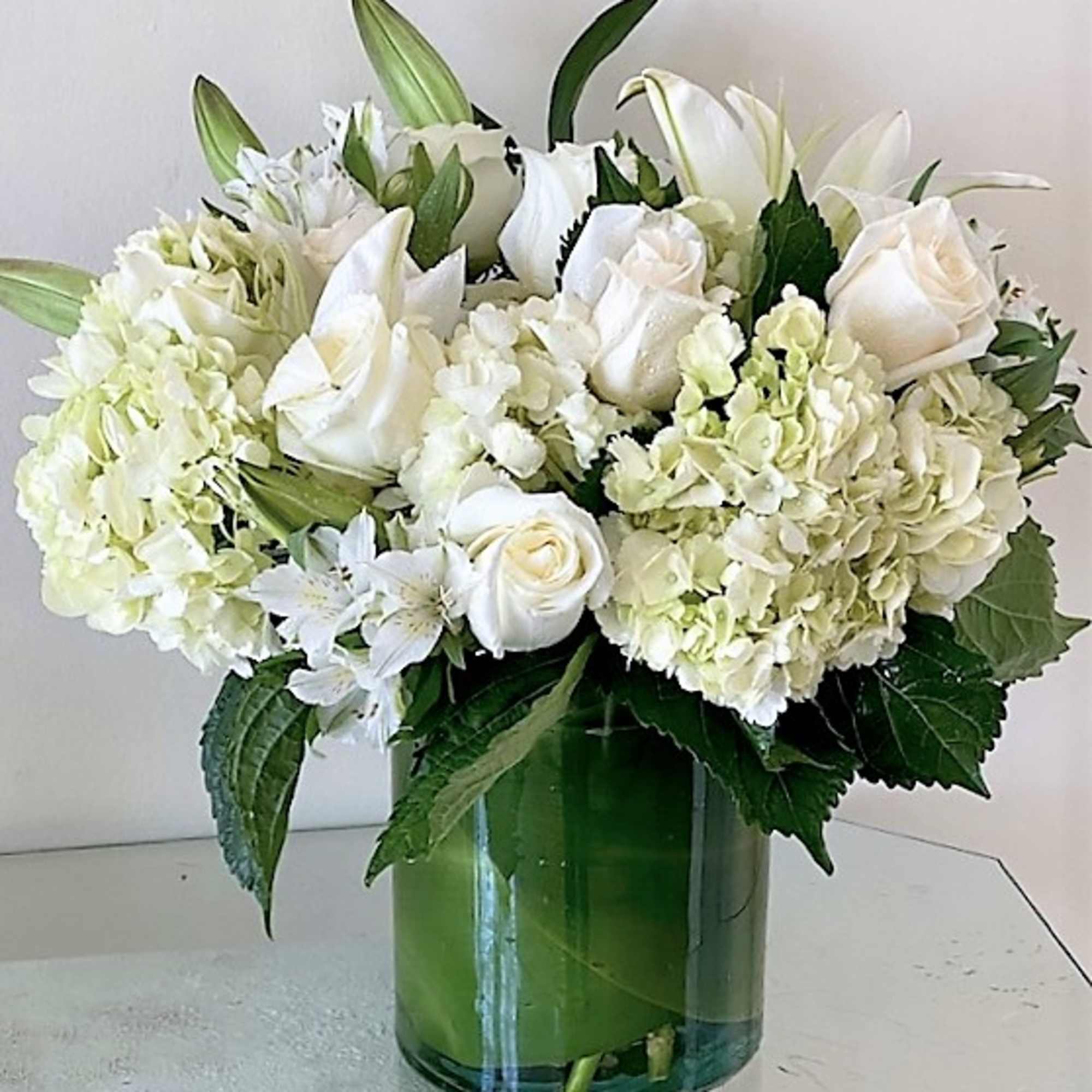 White flowers as shown arranged in a vase. Photos shown are Standard White flowers as shown arranged in a vase. Photos shown are Standard