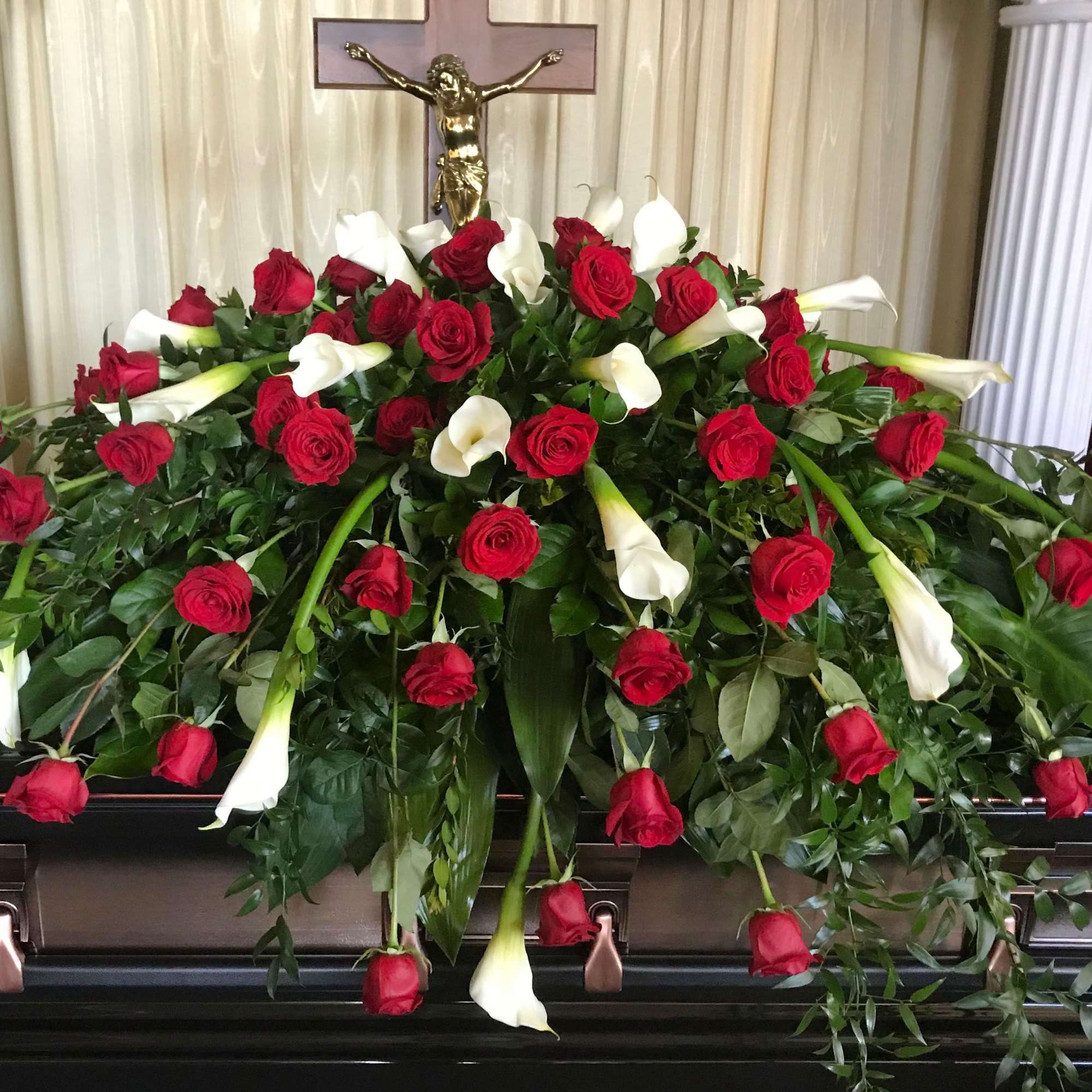 Graceful and reverent, this casket spray combines classic red roses with elegant Graceful and reverent, this casket spray combines classic red roses with elegant