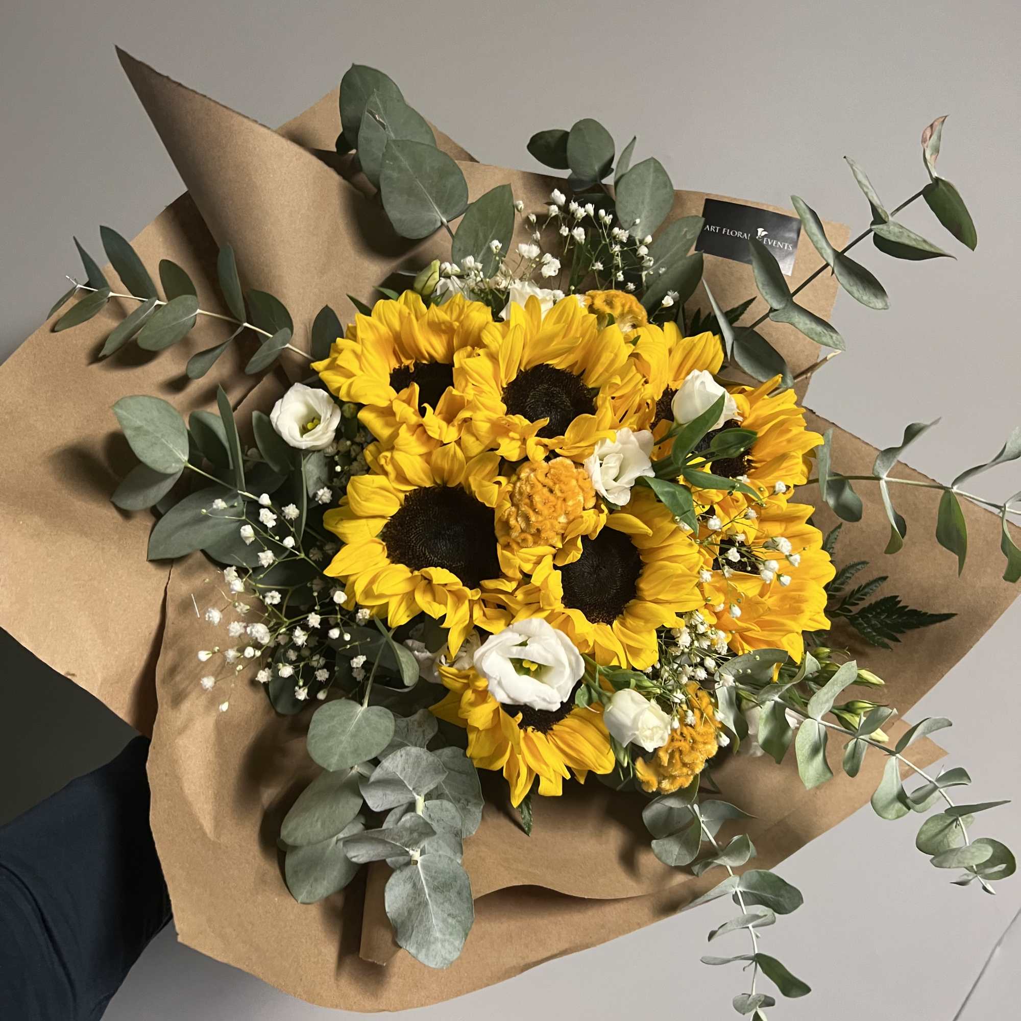 Sunflowers, eucalyptus, and filler white florals
wrapped with brown craft paper or waterproof
