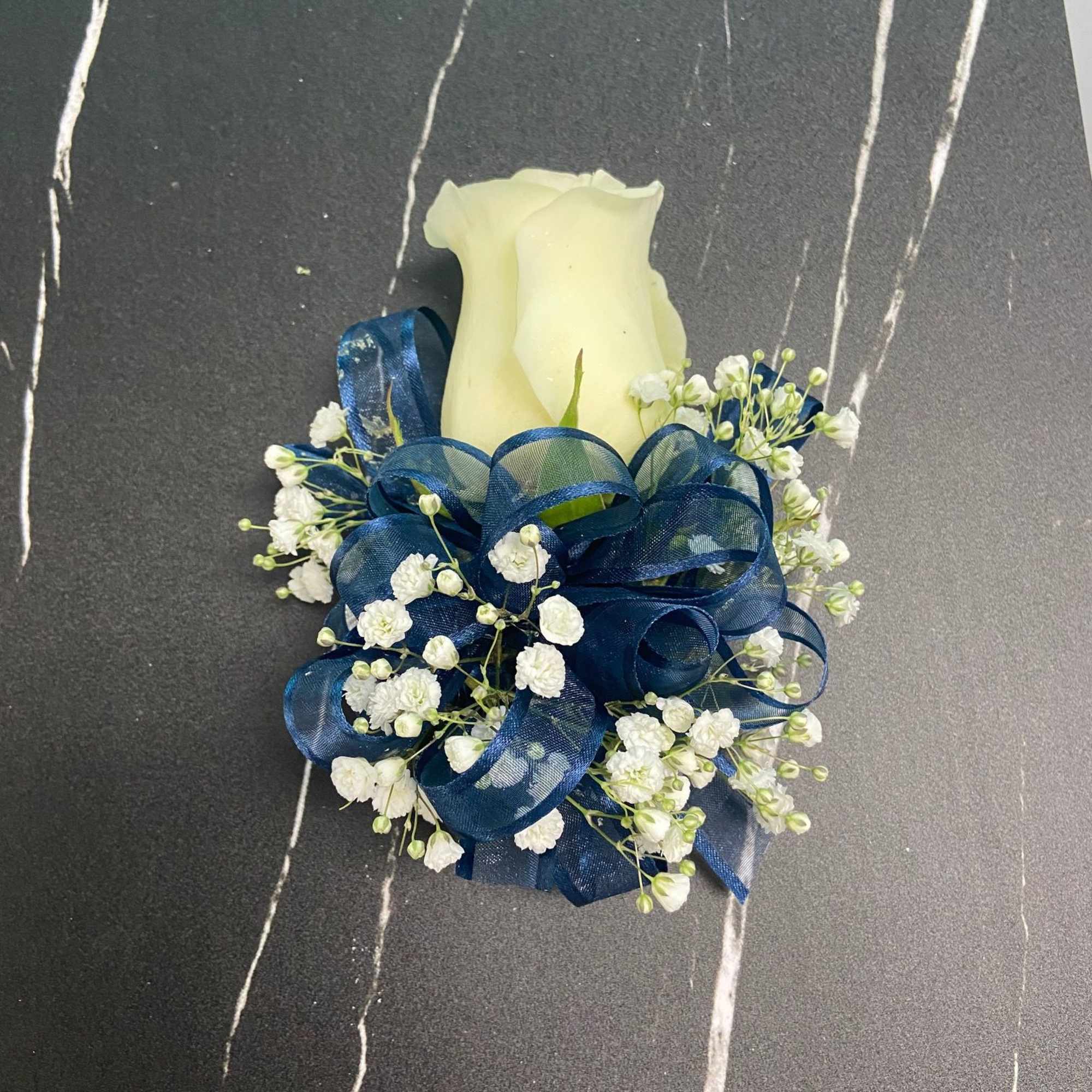 A beautiful rose corsage with ribbon and babies breath. Available in White A beautiful rose corsage with ribbon and babies breath. Available in White