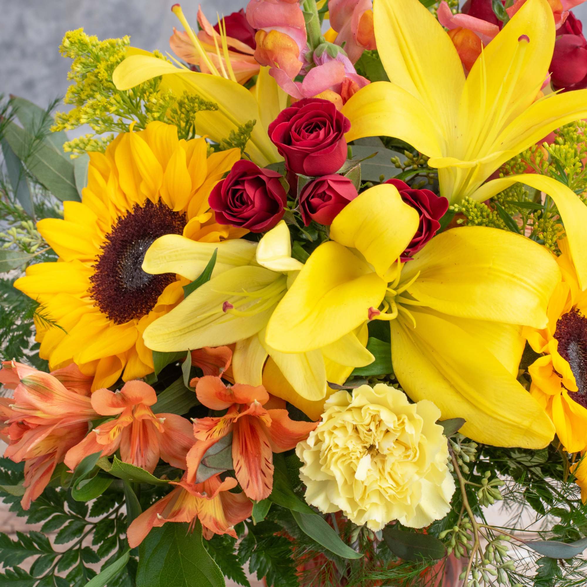 Bright yellow sunflowers, red spray roses, snap dragons and lilies among some Bright yellow sunflowers, red spray roses, snap dragons and lilies among some