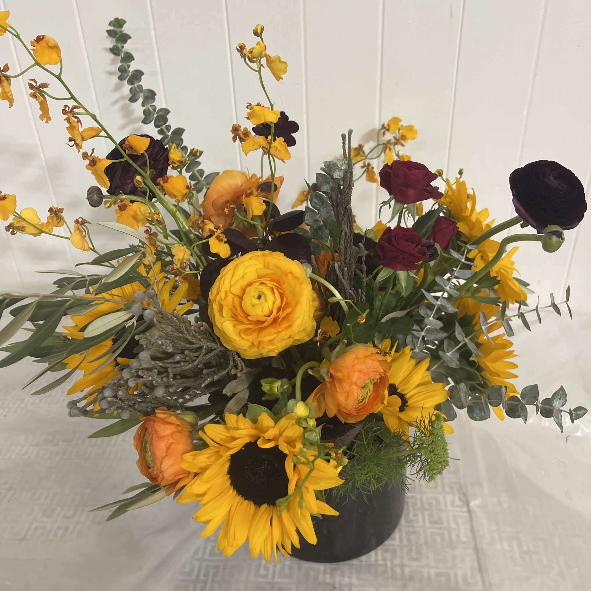 Floral arrangement in primarily yellow and orange hues designed in the spirit