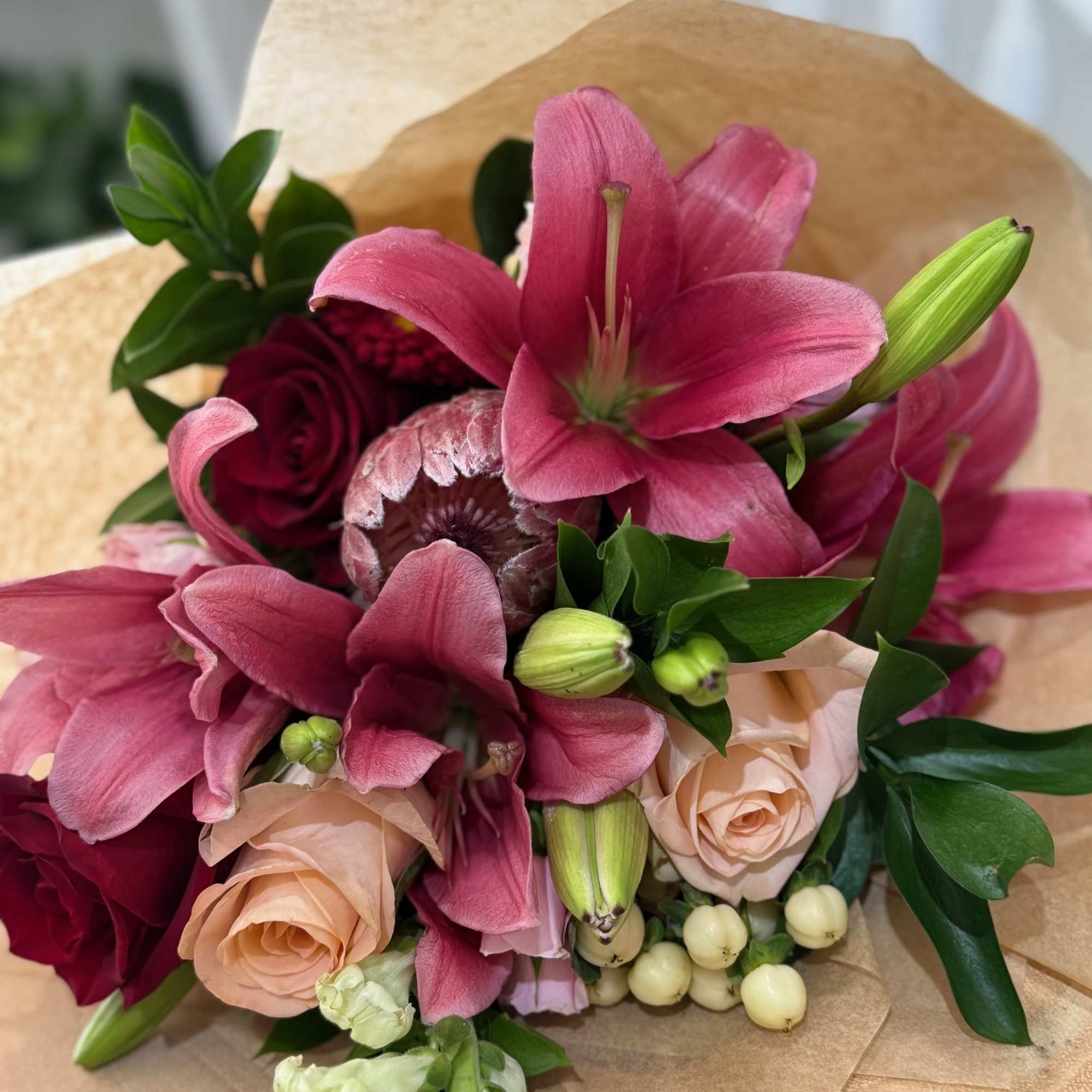 A breathtaking mix of two king proteas, classic lilies, and elegant roses