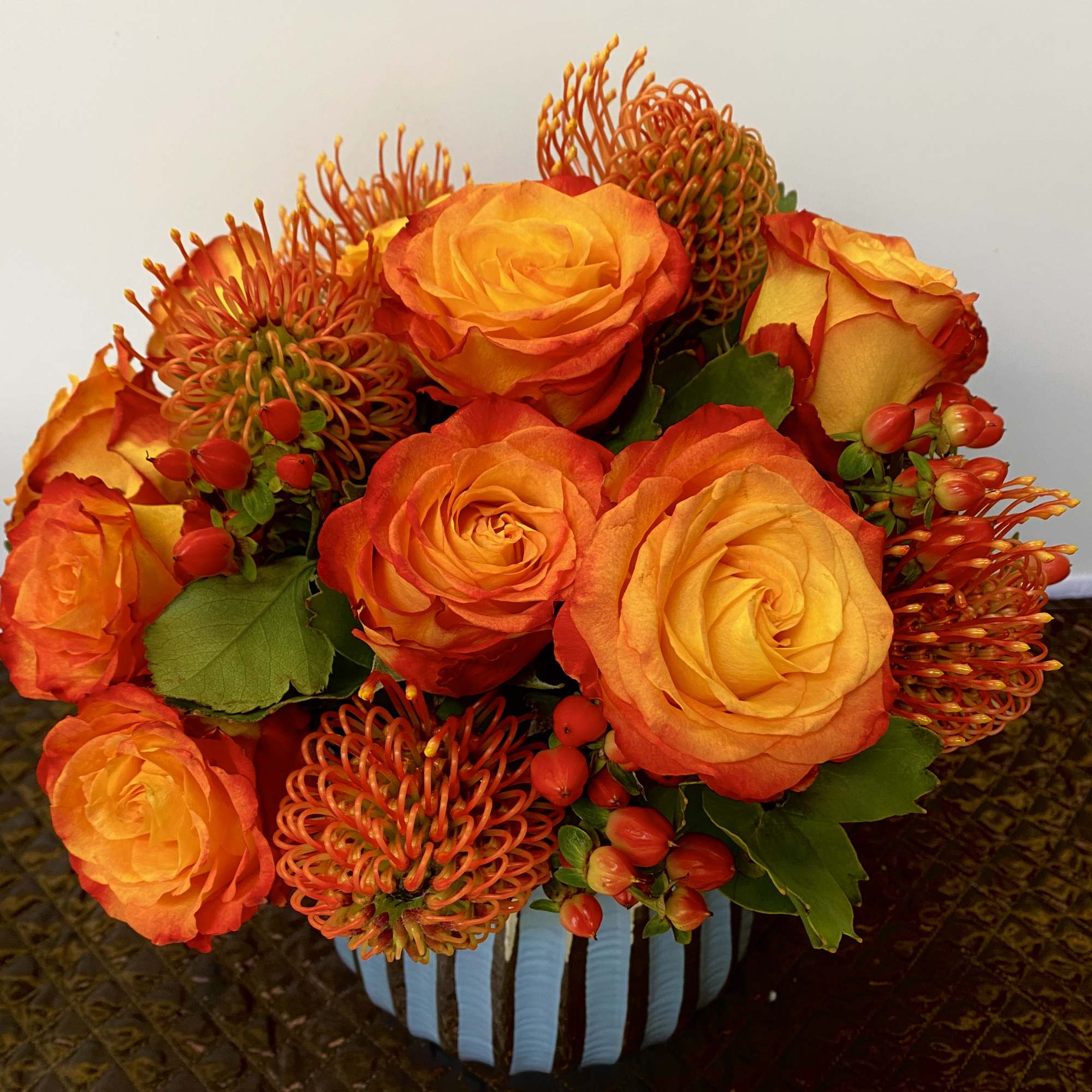 in a very nice vase with a orange roses and pink cushions