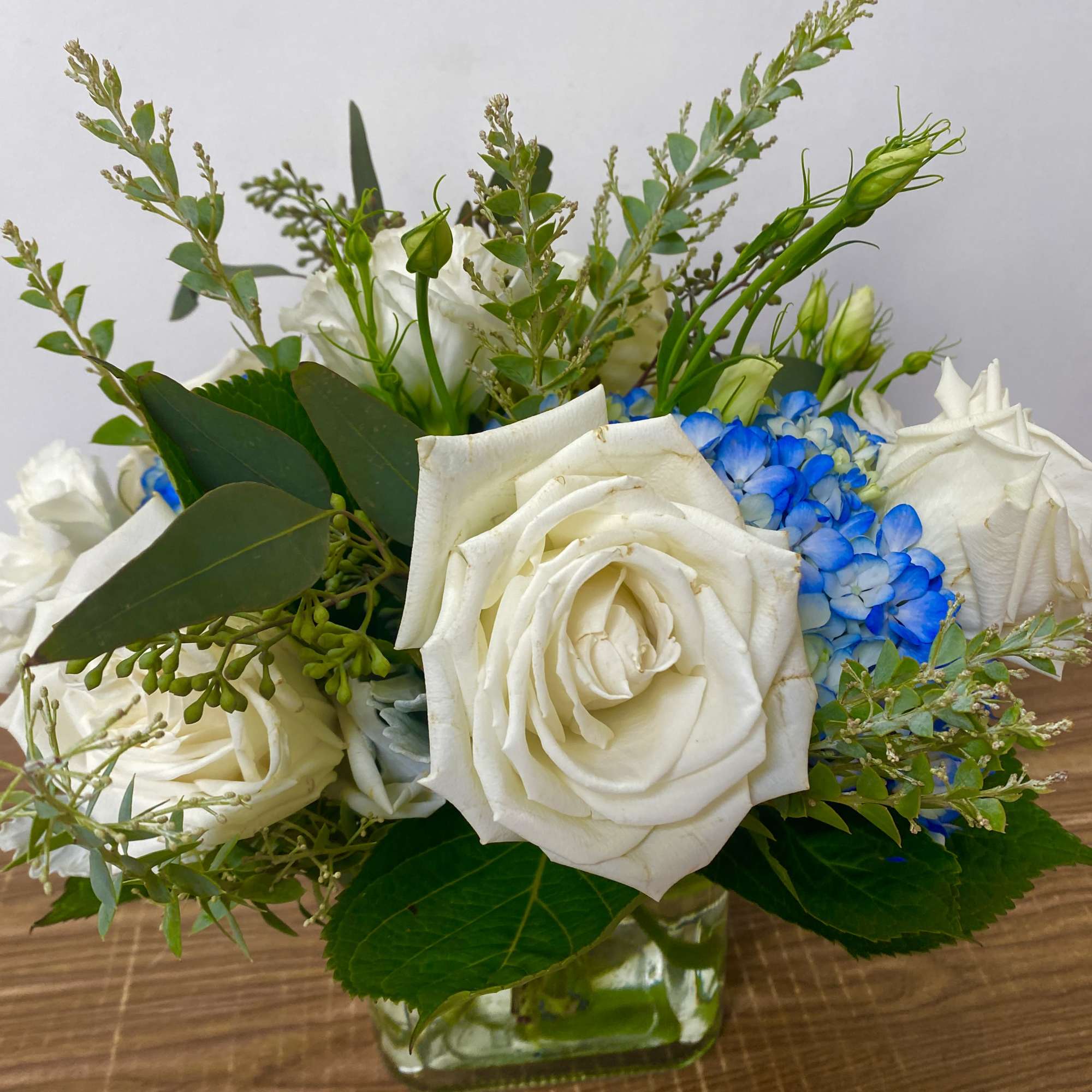 in a glass vase hydrangeas, roses, orchids