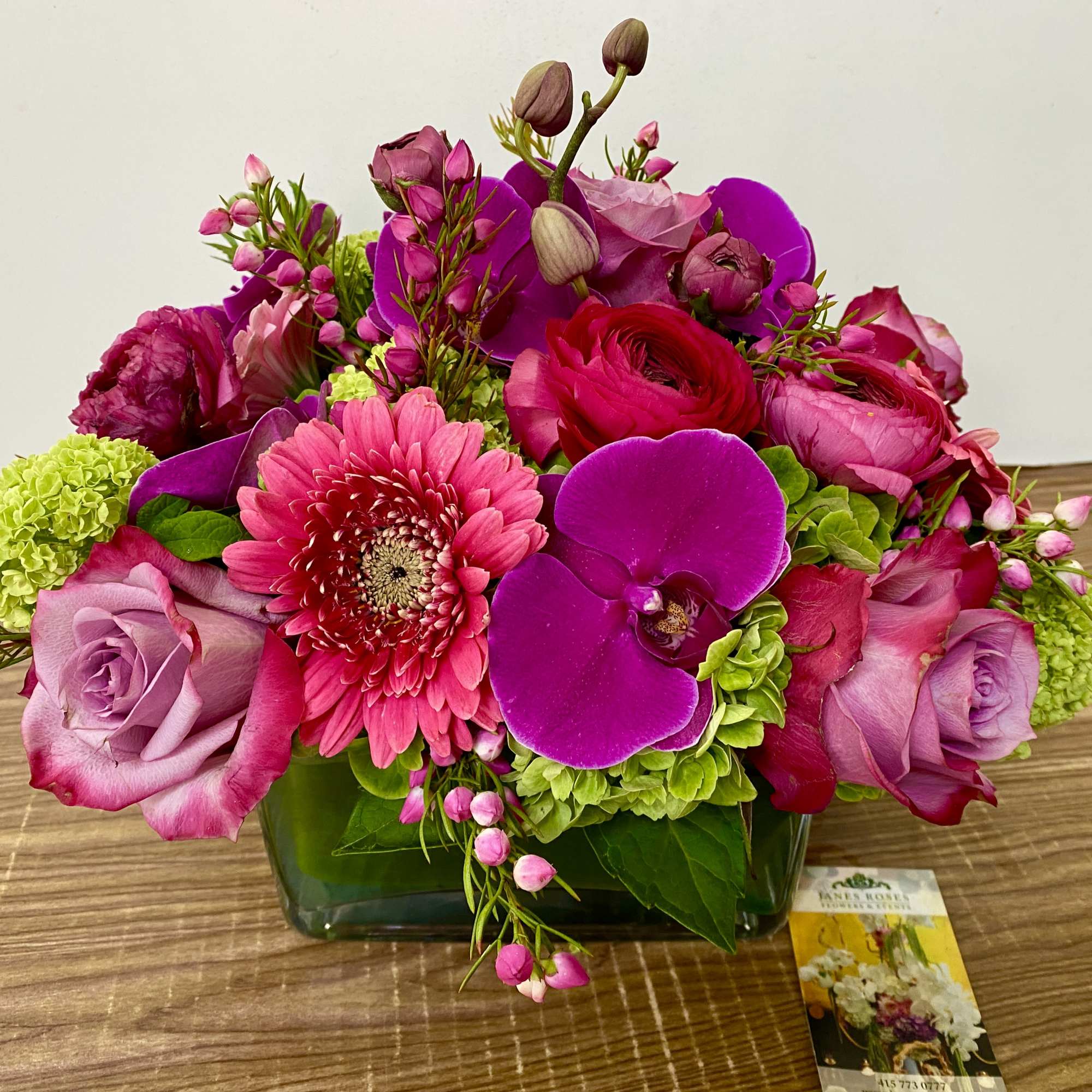 Green Hydrangea, Pink Gerberas, Purple Orchids in square glass vase and green