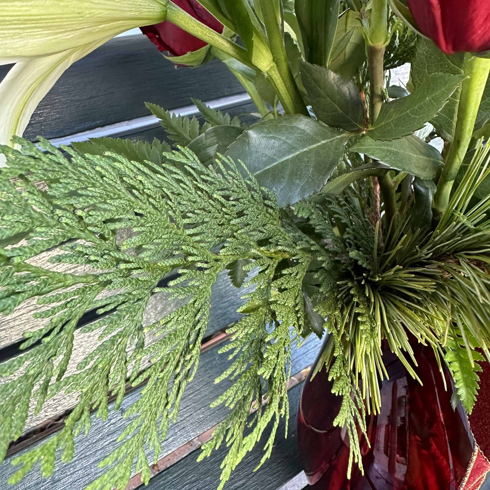 Seasonal designed arrangement in a vase with fresh assorted christmas greens, fresh