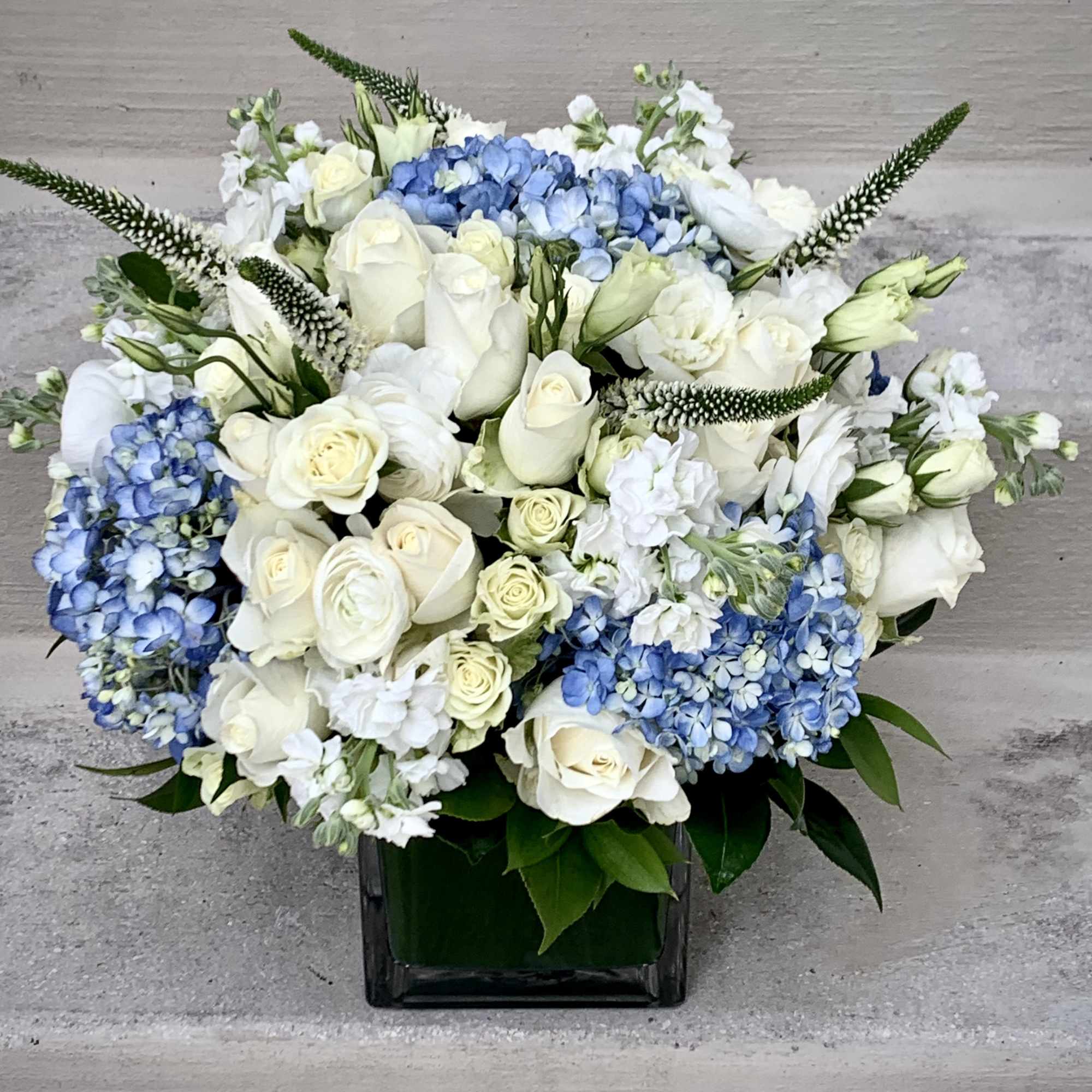 This luxury arrangement contains mixed florals such as roses, blue and white This luxury arrangement contains mixed florals such as roses, blue and white