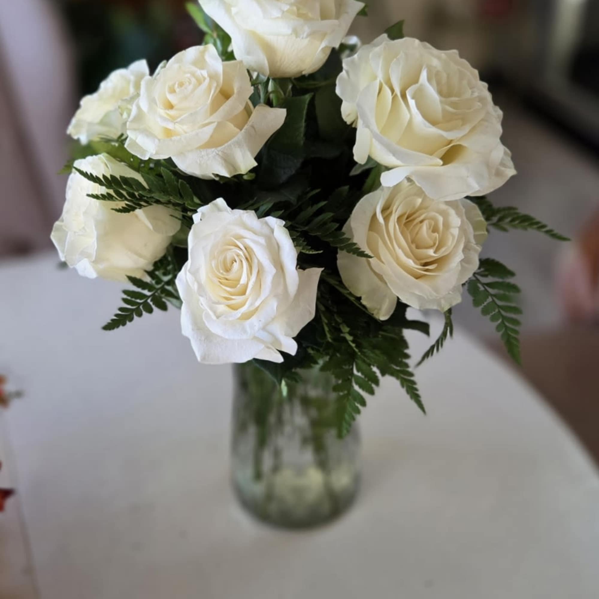 One dozen white roses with fillers and greens