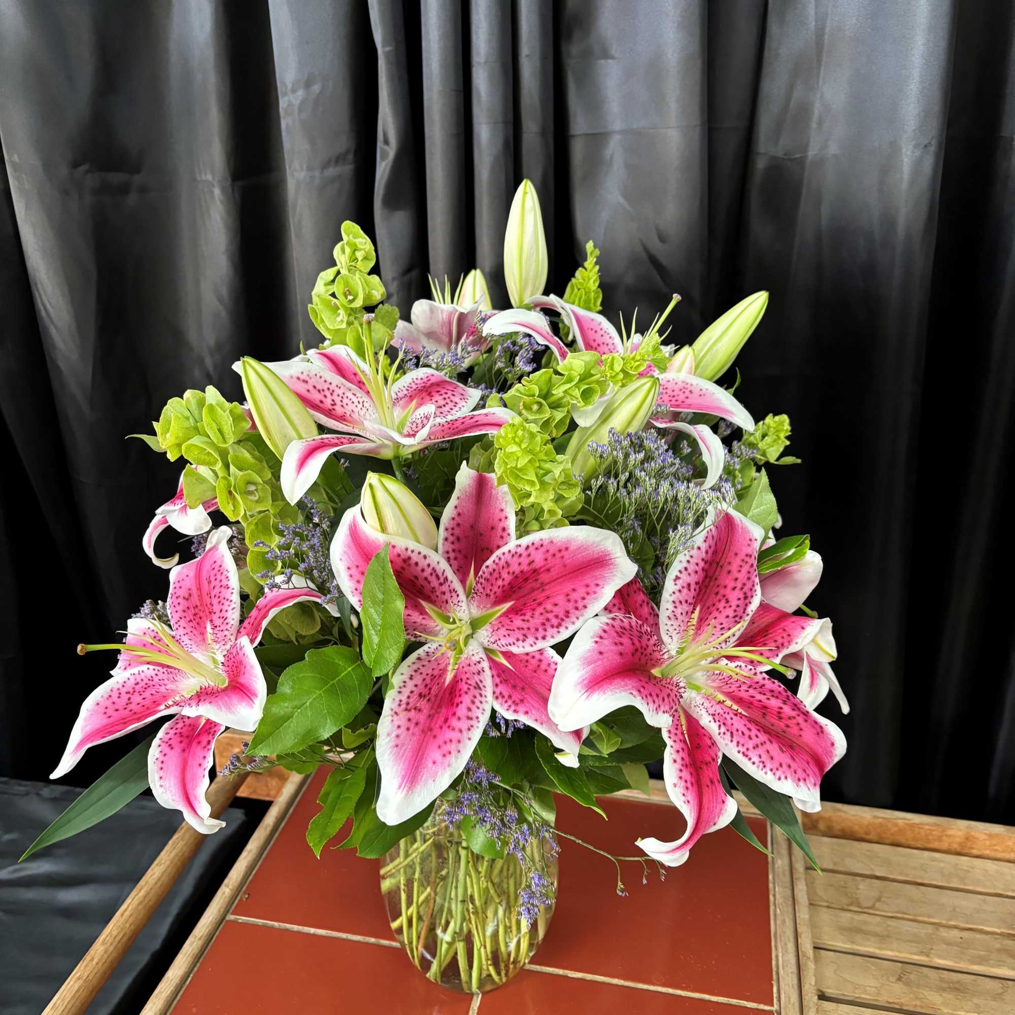 A traditional arrangement of Stargazer lilies and quality greens and filler A traditional arrangement of Stargazer lilies and quality greens and filler